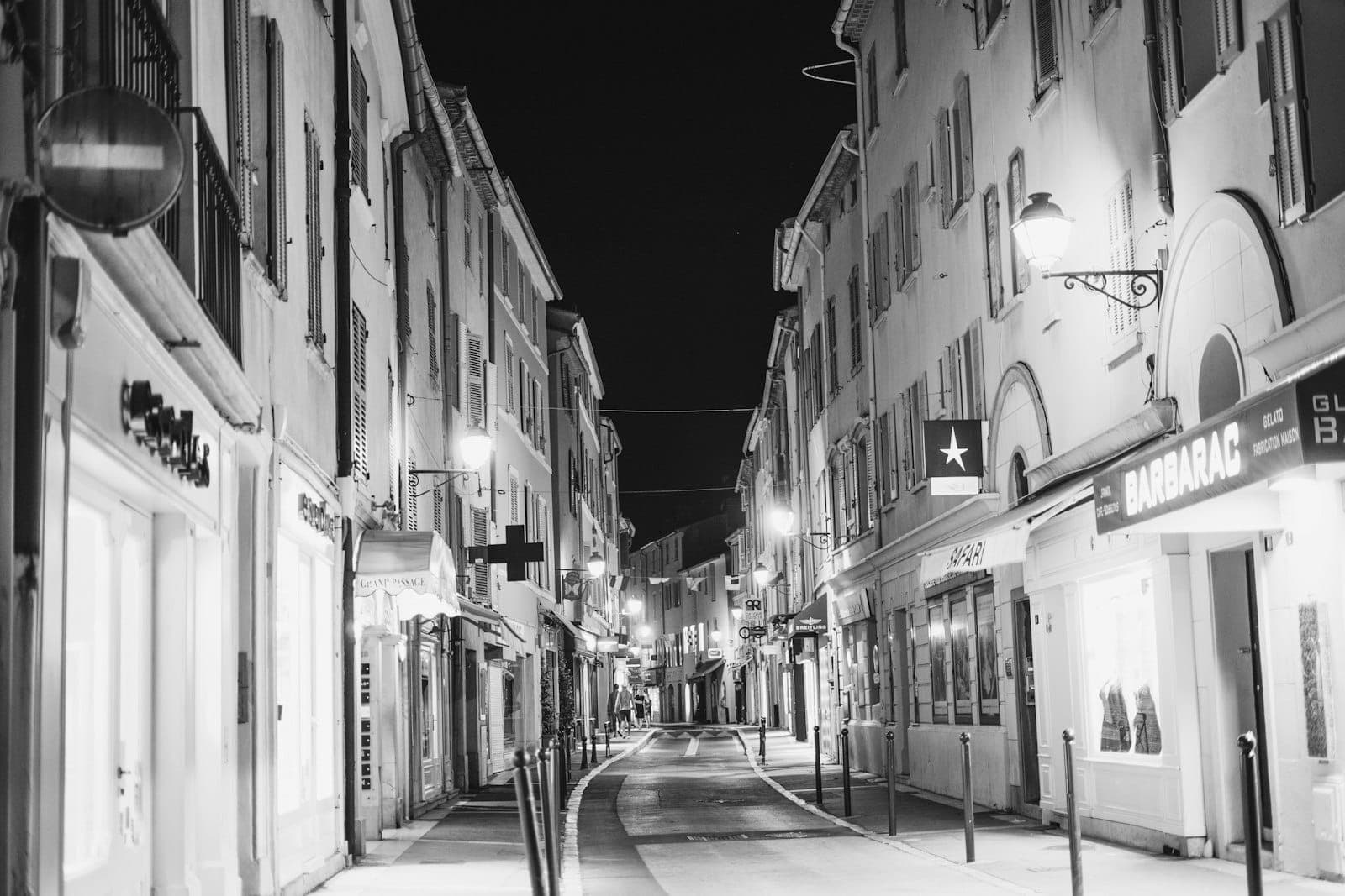 Чёрно-белая фотография Rue d'Antibes в Каннах ночью: улица, обрамлённая бутиками, магазинами и мягко освещёнными витринами.