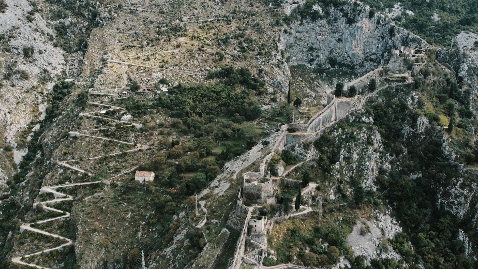 Vue aérienne du rempart de la forteresse de Kotor zigzaguant sur la montagne, avec des ruines et un paysage rocheux spectaculaire clairement visible.