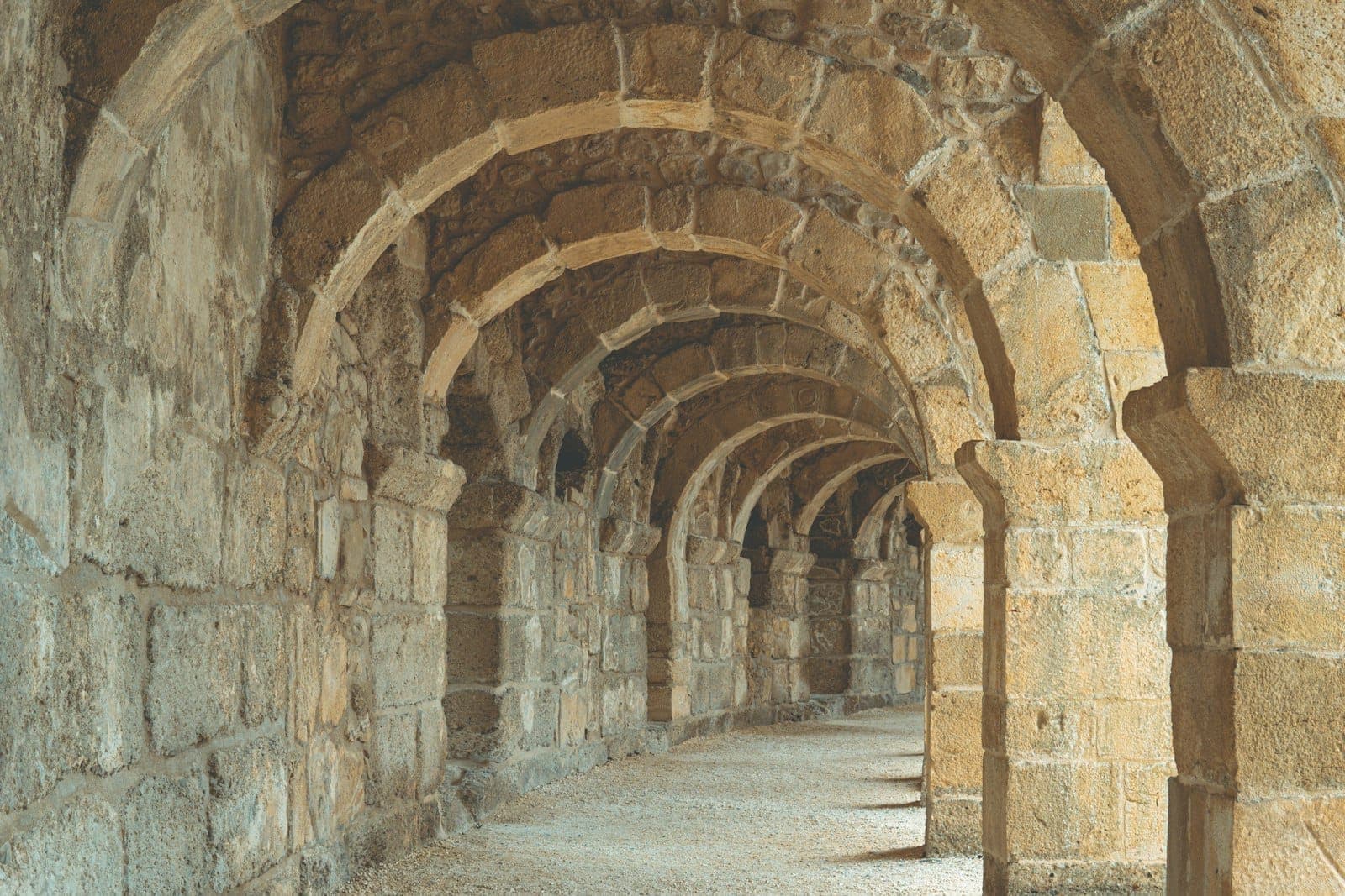 Eine Reihe antiker Steinbögen, die einen gewölbten Korridor bilden, wahrscheinlich Teil der römischen Ruinen von Perge in der Nähe von Antalya.