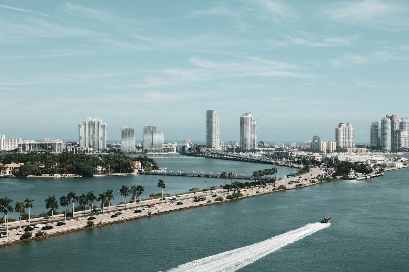 Vue aérienne de Miami montrant une autoroute reliant le continent et Miami Beach, avec de grands immeubles et une eau bleue des deux côtés.