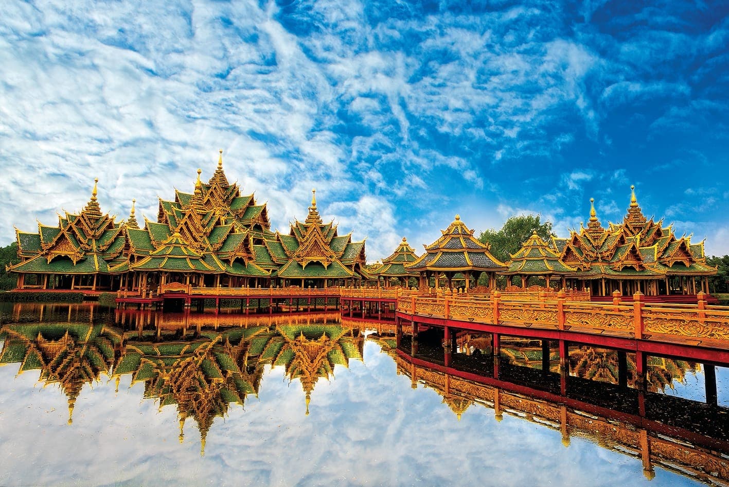 Pavillons thaïlandais traditionnels à Ancient City Muang Boran près de Bangkok, avec leurs toits ouvragés se reflétant dans l'eau sous un ciel spectaculaire