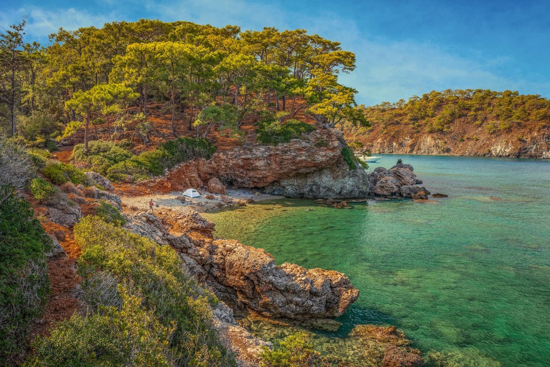 Felsige, bewaldete Küste und ein kleiner abgelegener Strand mit klarem türkisfarbenem Wasser westlich von Antalya, Türkei.