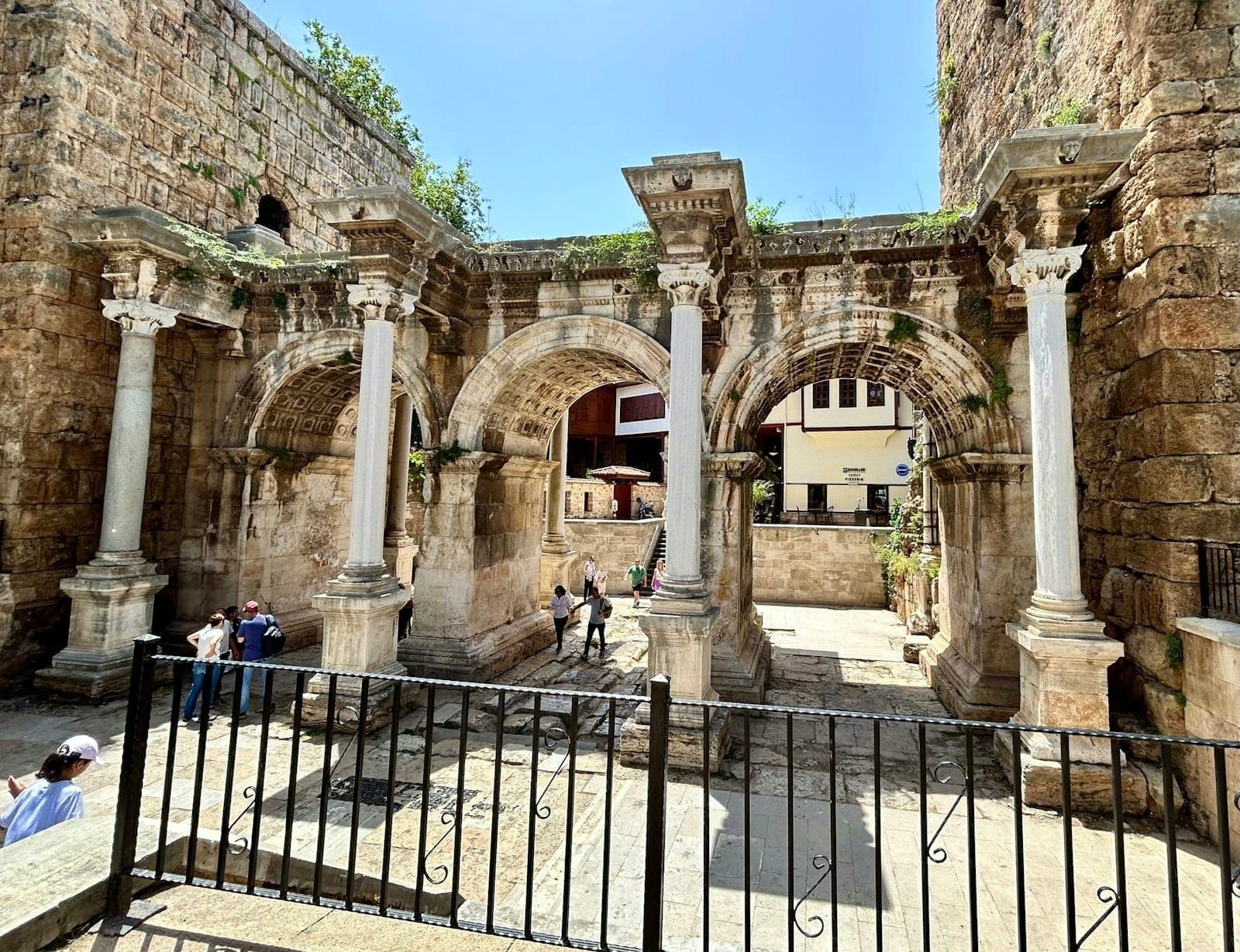 Steinbögen und Säulen des Hadrianstor, mit Menschen, die unter dem antiken Bauwerk im Zentrum von Antalya spazieren.