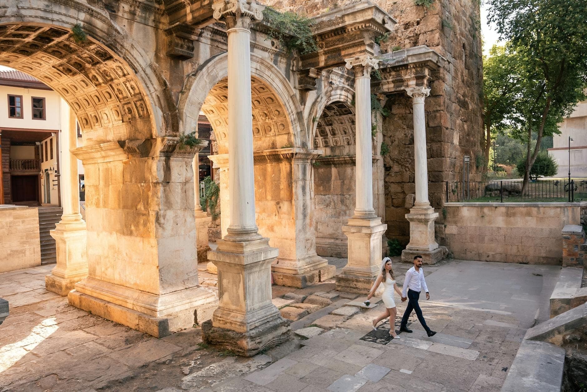Ein Paar spaziert Hand in Hand unter den antiken Marmorbögen des Hadrianstor im historischen Altstadtviertel von Antalya, Kaleiçi.