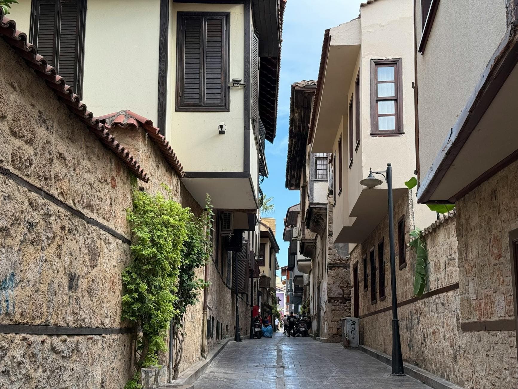 Rue étroite bordée de maisons historiques en pierre et de balcons en bois en surplomb dans la vieille ville d'Antalya.