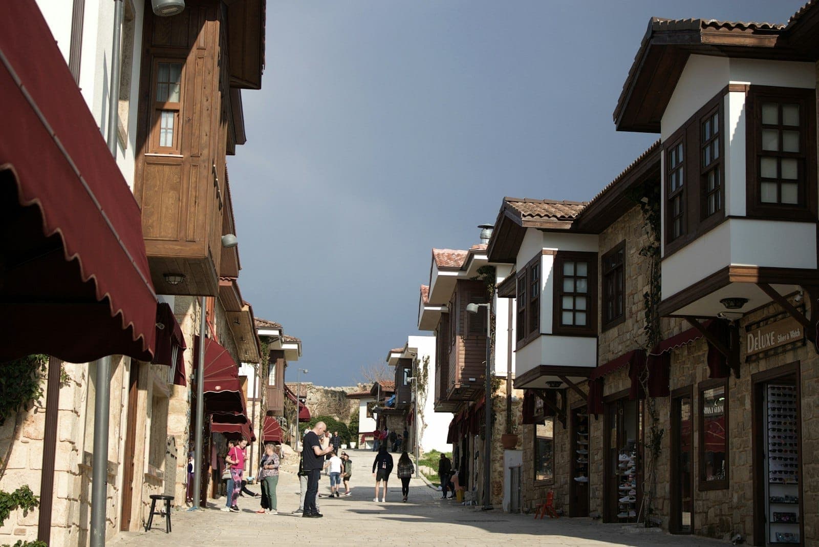 Des touristes se promènent dans une rue ensoleillée et propre de la vieille ville d'Antalya, bordée de maisons traditionnelles de style ottoman.