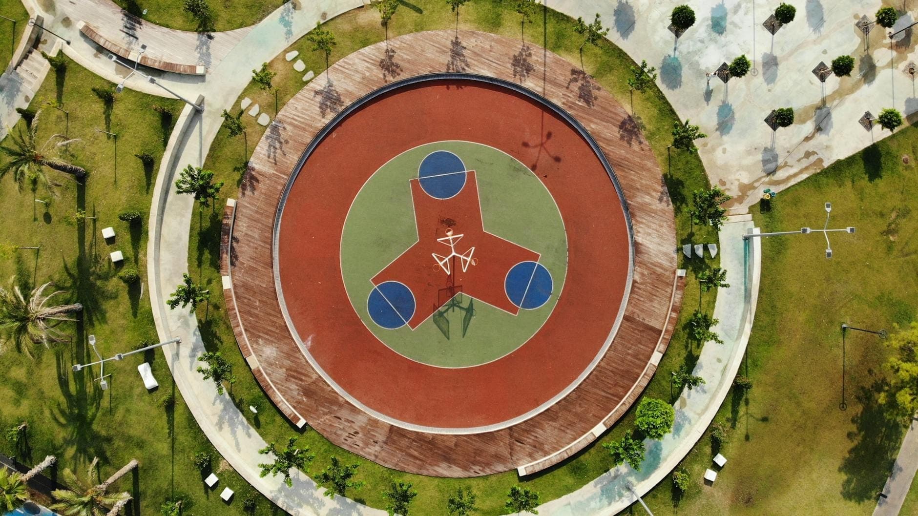 Vue aérienne d'un parc urbain aménagé à Antalya avec une grande aire de jeux ou de sport circulaire et moderne entourée de pelouses vertes et d'allées.