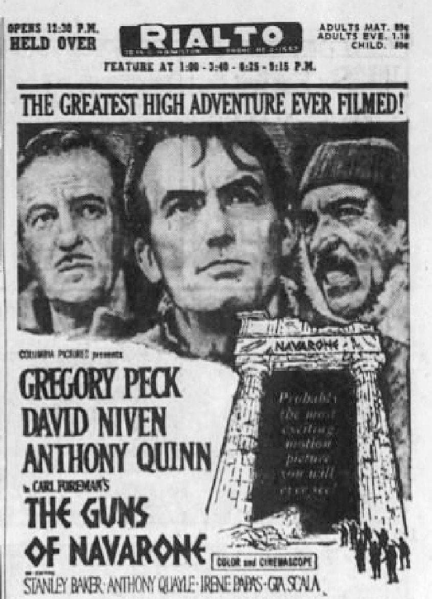 Zabytkowy czarno-biały plakat filmowy 'The Guns of Navarone' z ilustrowanymi portretami trzech aktorów nad kamiennym łukiem.