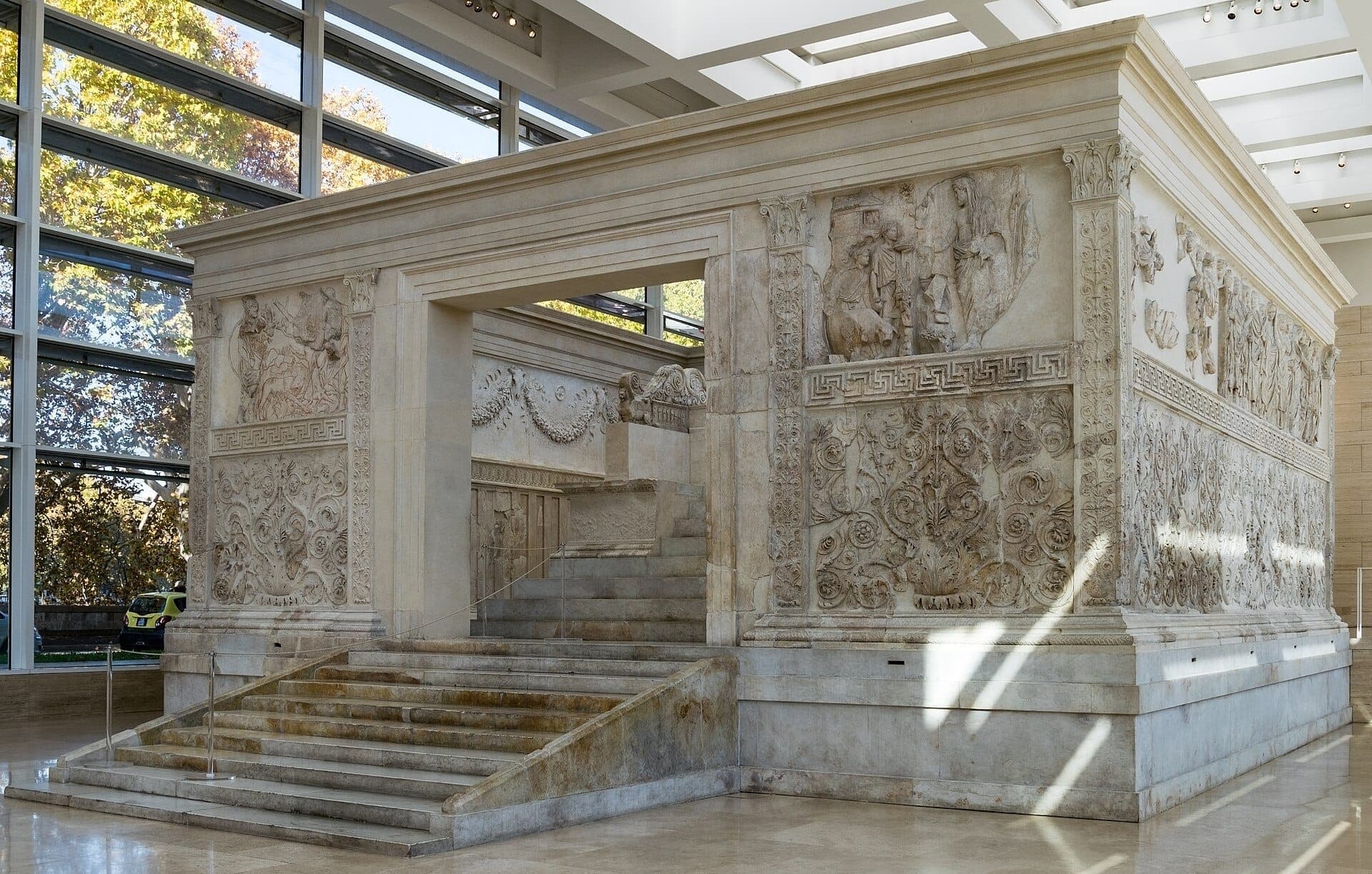 Ara Pacis Augustae tại Rome, với những phù điêu cẩm thạch tinh xảo và cầu thang rộng bên trong một gian trưng bày kính hiện đại sáng rõ.