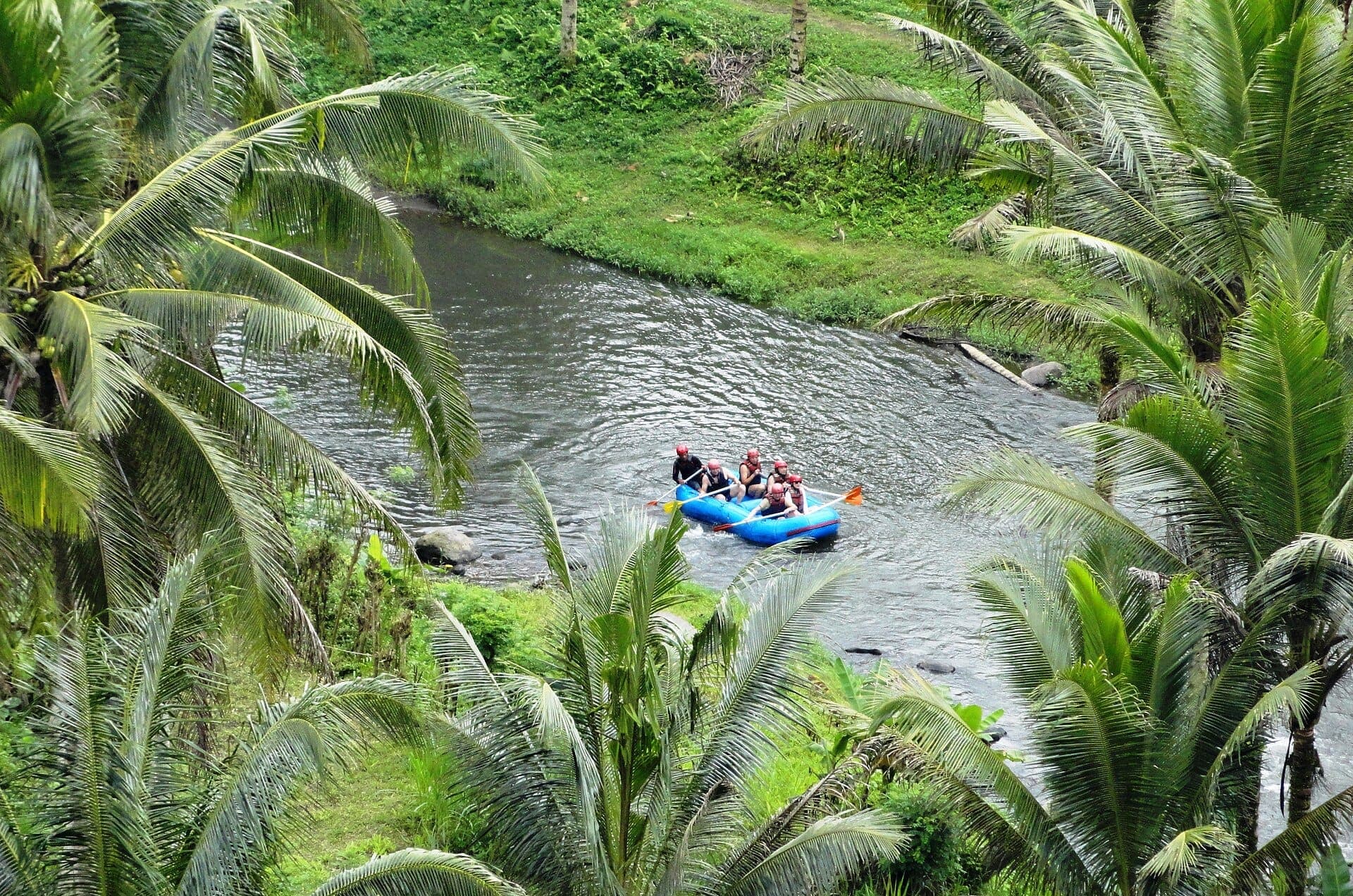 Rafters navigate Ayung River's gentle rapids amid Bali's dense rainforest, dramatic gorges, and intricate riverside reliefs near Ubud.