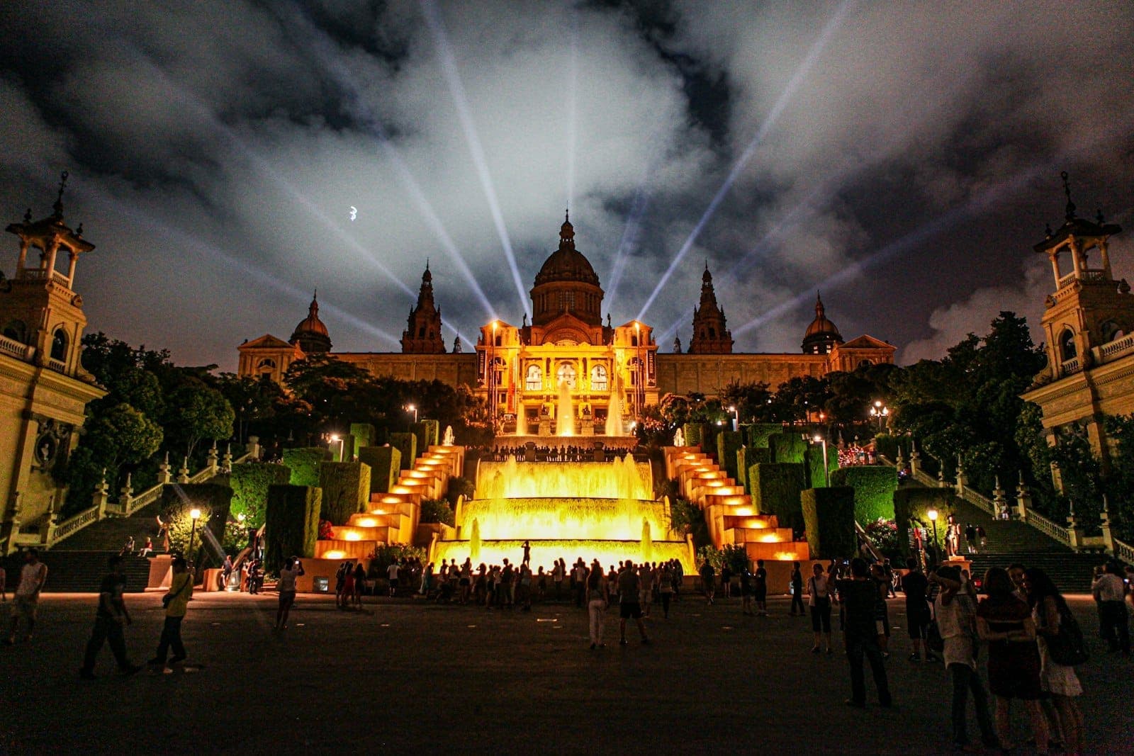 Nocny widok na Palau Nacional w Barcelonie na Montjuïc z oświetlonymi fontannami i tłumami przed budynkiem
