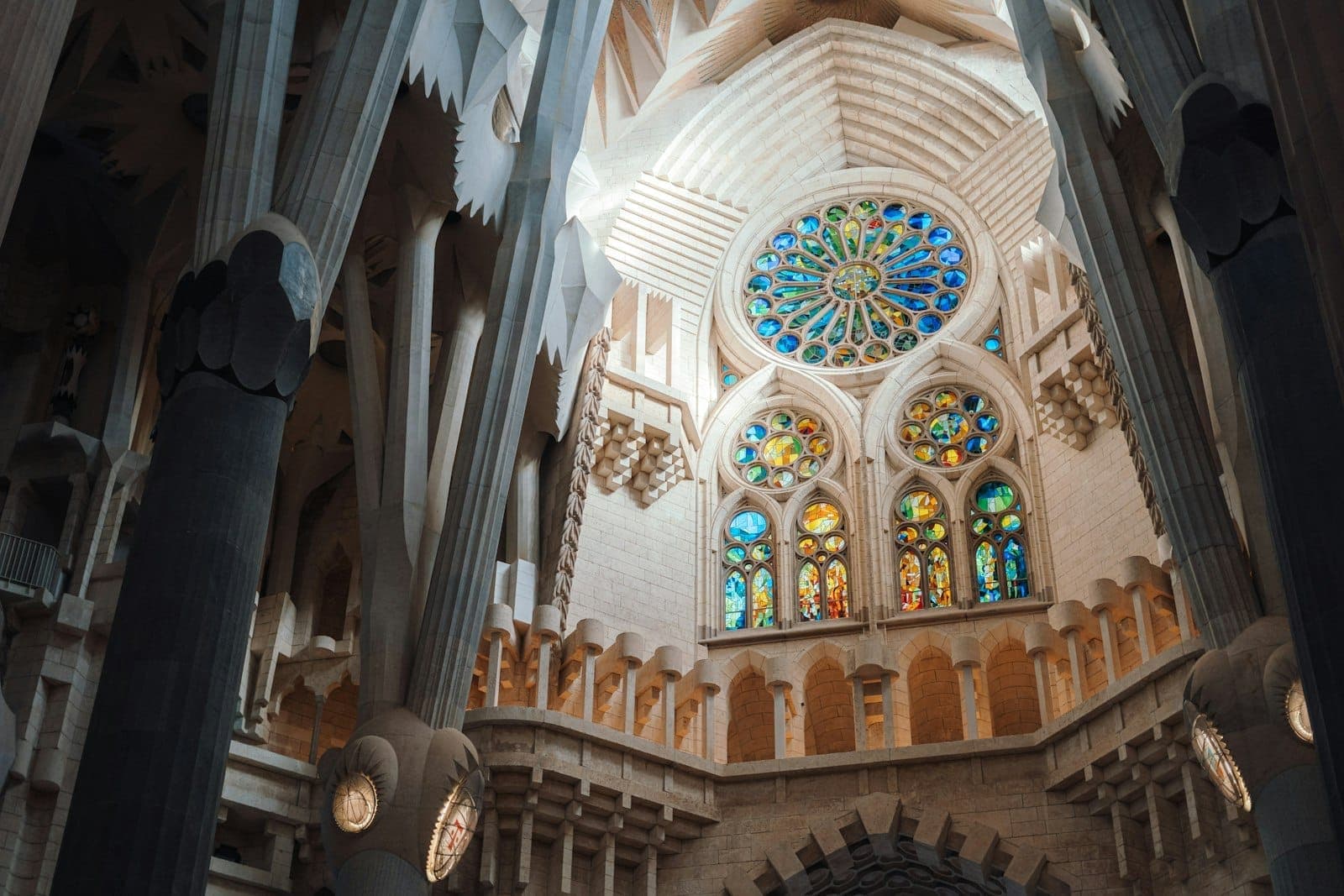 Vista interior de la Sagrada Família con las columnas orgánicas de Gaudí, vidrieras de colores y elementos arquitectónicos detallados iluminados por luz natural.