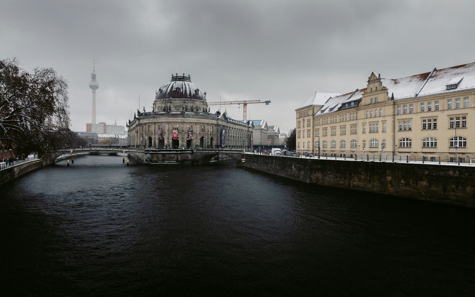 Winteransicht der Berliner Museumsinsel mit dem Bode-Museum, Schnee auf den Dächern und bedecktem Himmel