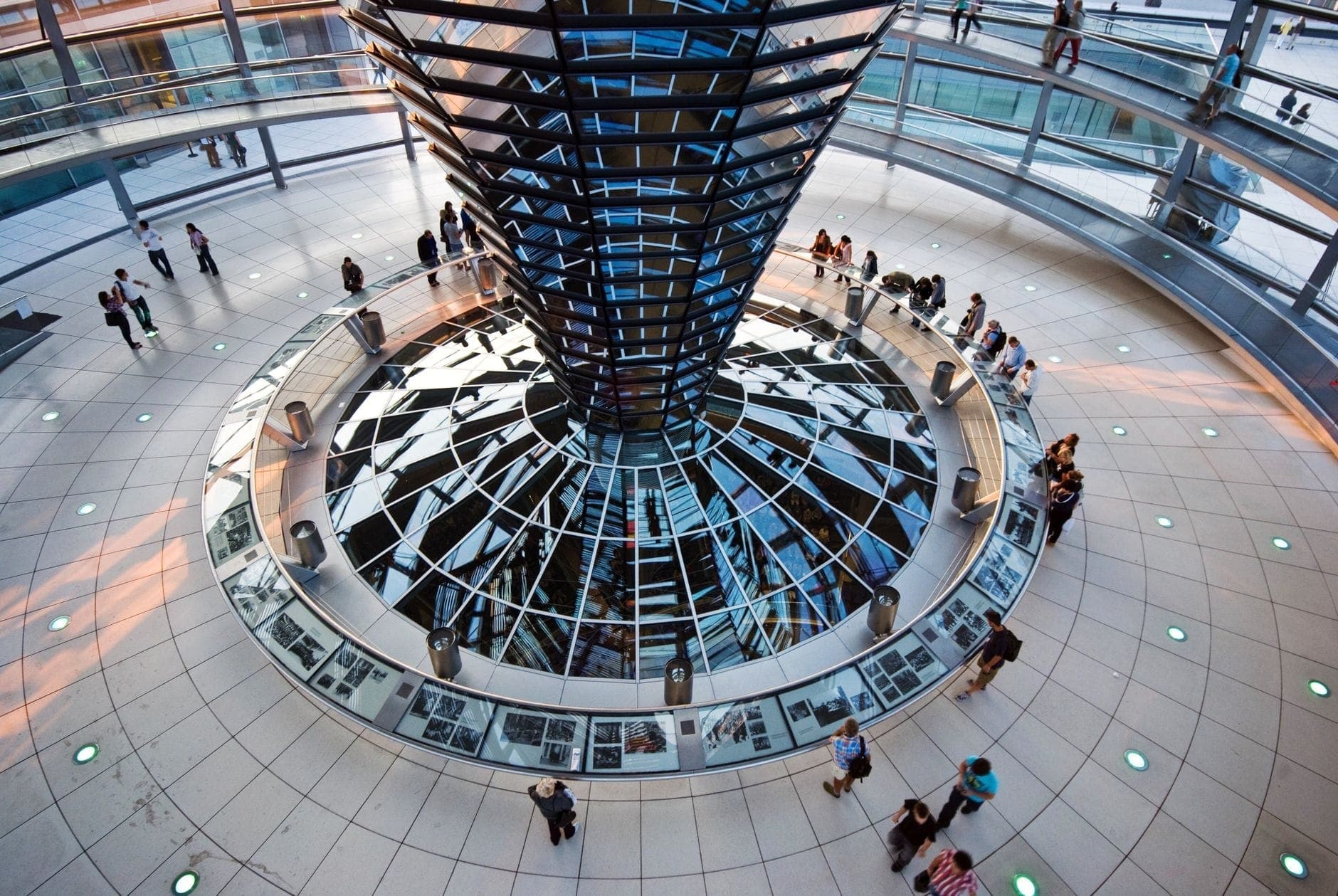 Vista dall'interno della cupola del Reichstag con rampe a spirale, imbuto a specchi e visitatori che esplorano il percorso circolare.