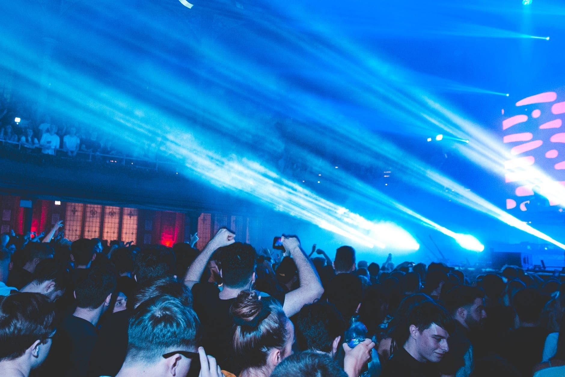 Discoteca de Berlín abarrotada con luces de escenario azules, multitud enérgica y animado ambiente nocturno