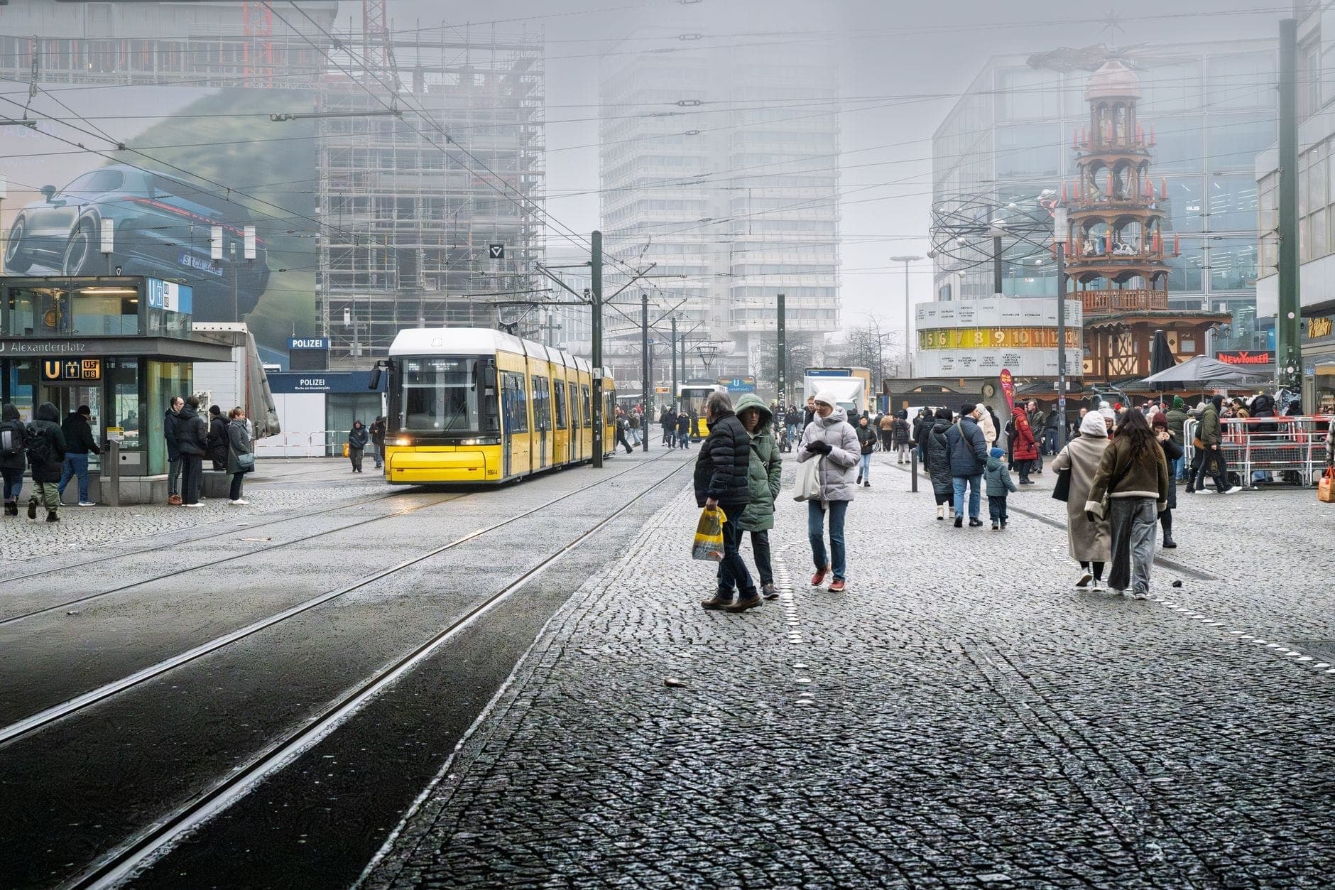 Plaza urbana concurrida en Berlín con personas caminando, tranvía amarillo y edificios modernos, típica de las zonas turísticas propensas a los carteristas.