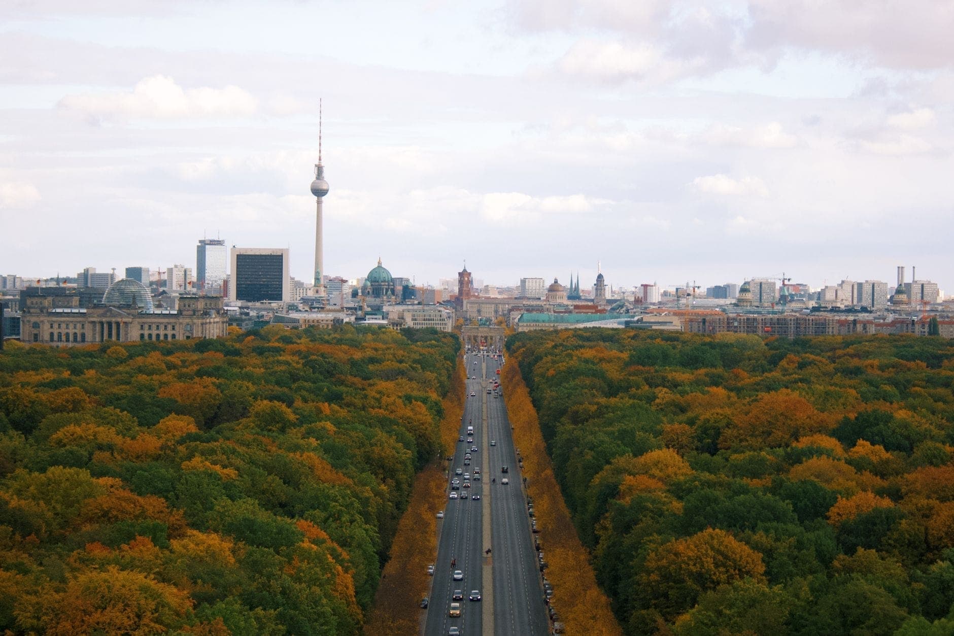 วิวเมือง Berlin แบบกว้างพร้อมหอโทรทัศน์ Fernsehturm อันโด่งดัง ถนนสายหลักกลางเมือง และต้นไม้สีสันฤดูใบไม้ร่วงในเบื้องหน้า