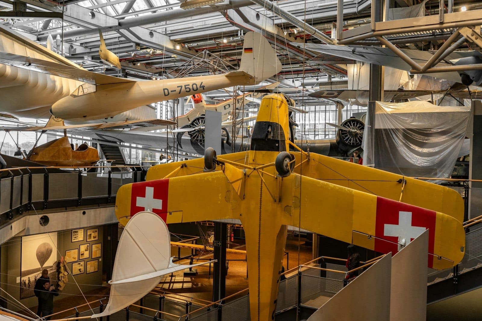 Wnętrze Deutsches Technikmuseum Berlin z rodzinami i dziećmi odkrywającymi kolorowe samoloty i eksponaty w jasnej, interaktywnej galerii.