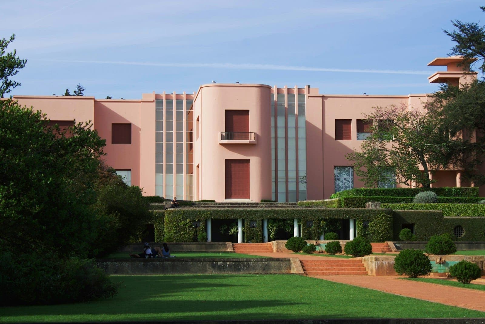 Porto, Portekiz'de mavi bir gökyüzü altında bakımlı bahçelerle çevrili Serralves Müzesi'nin pembe Art Deco cephesi.