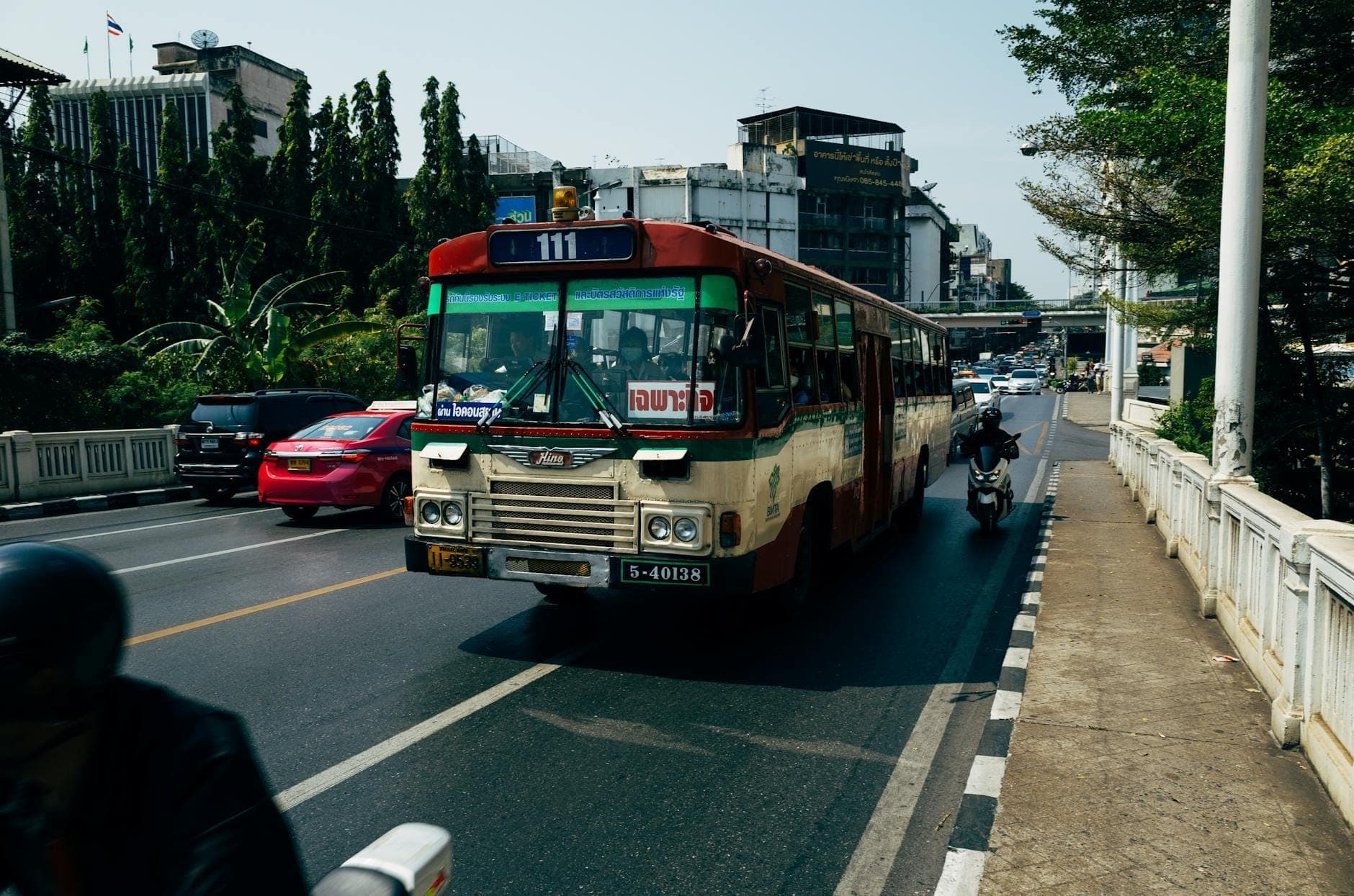 Bangkok'ta trafikte bir caddede toplu taşıma otobüsü; şehirdeki ulaşım seçeneklerini gösteriyor