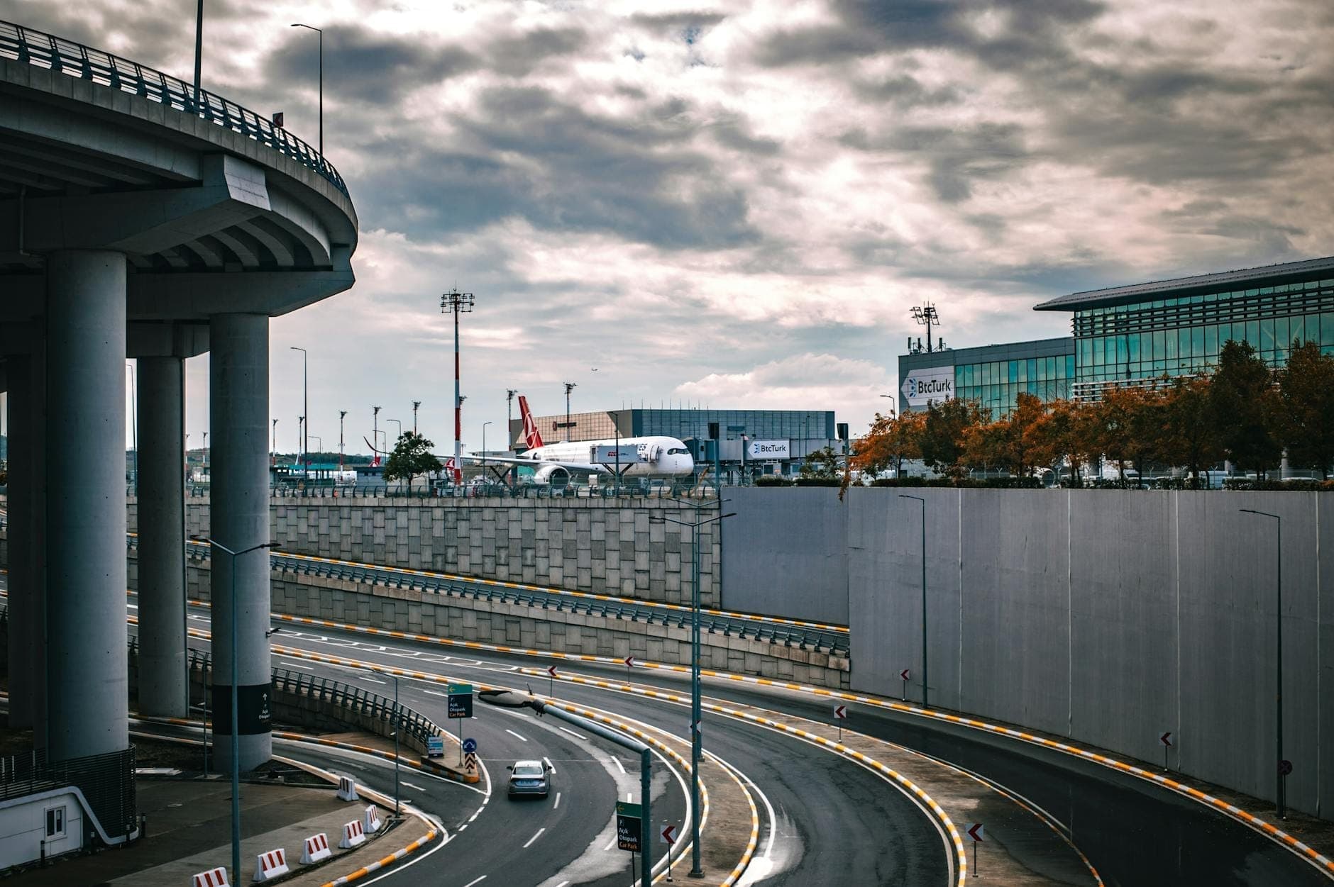 City-side view of Barcelona El Prat airport with planes, terminal buildings, and access roads on a cloudy day.