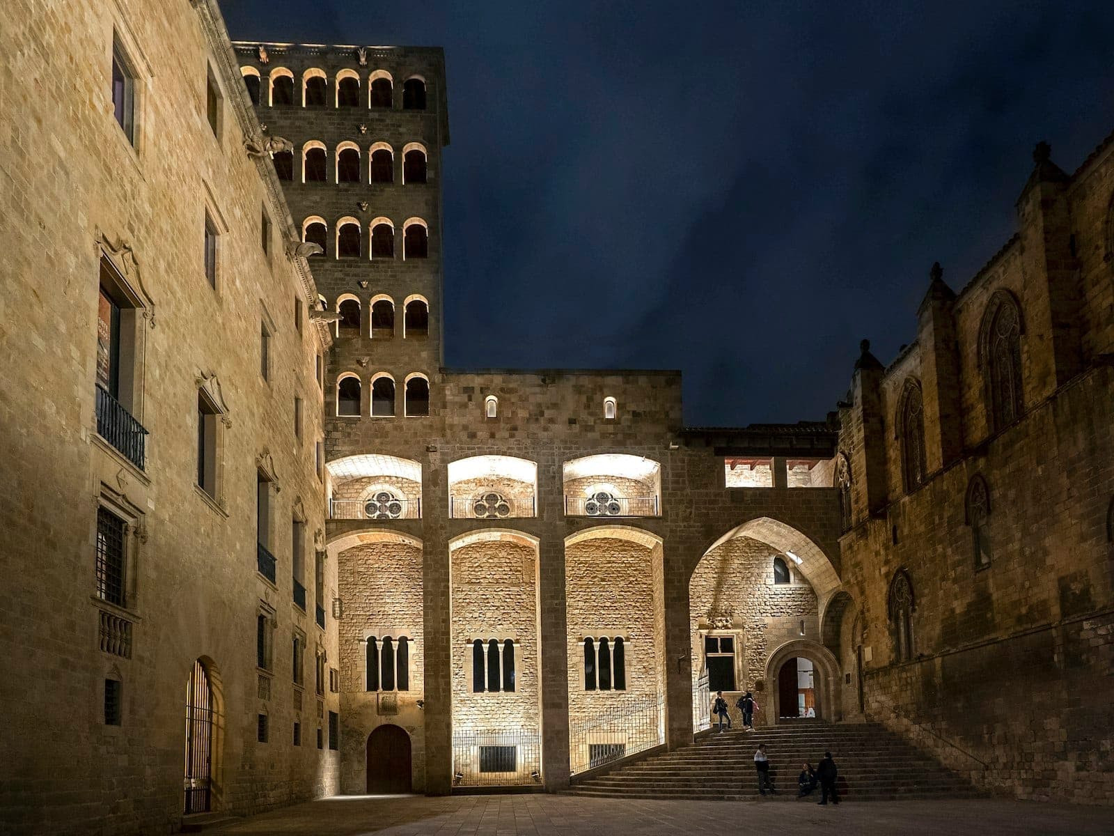 Nighttime view of Plaça del Rei in Barcelona, softly lit with only a few people and quiet atmosphere.
