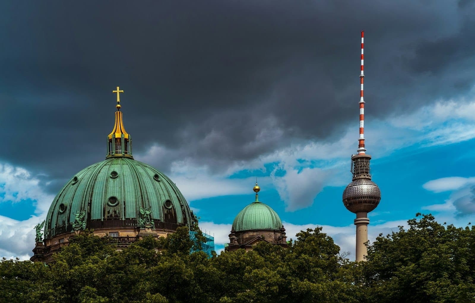 Catedral de Berlín y torre de televisión bajo un cielo dramático y parcialmente nublado, mostrando el horizonte de la ciudad y el clima variable.