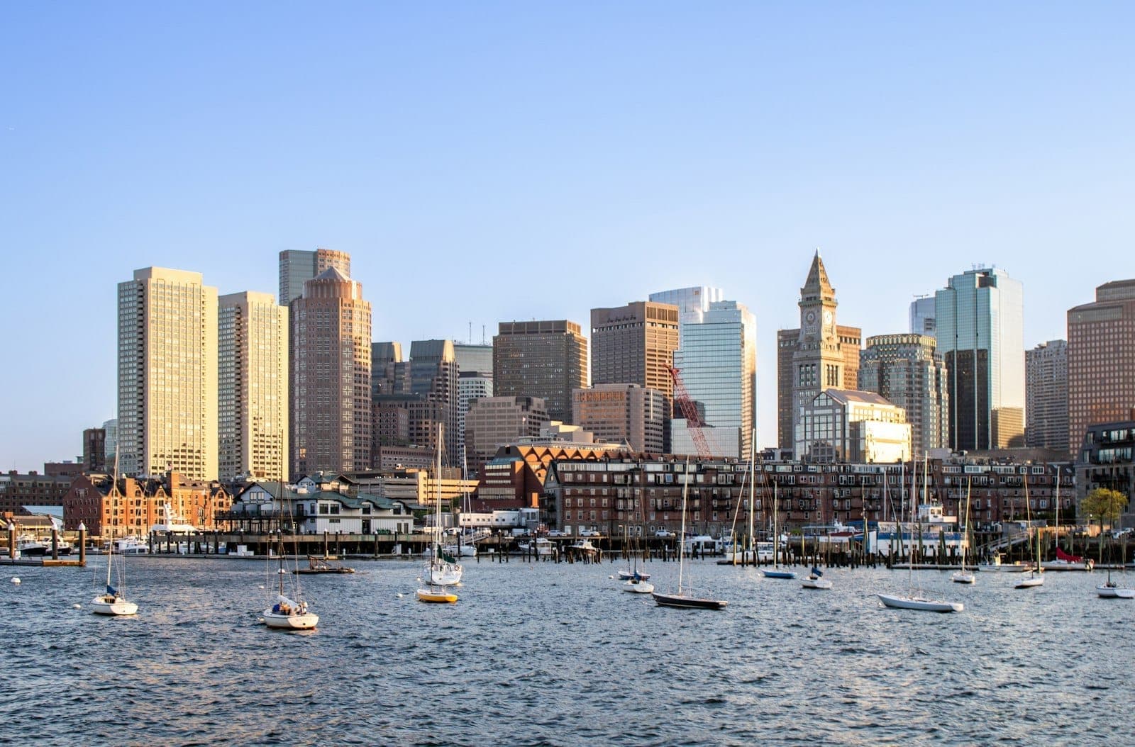 Horizon de Boston en été avec des voiliers et des yachts dans le port sous un ciel bleu dégagé.
