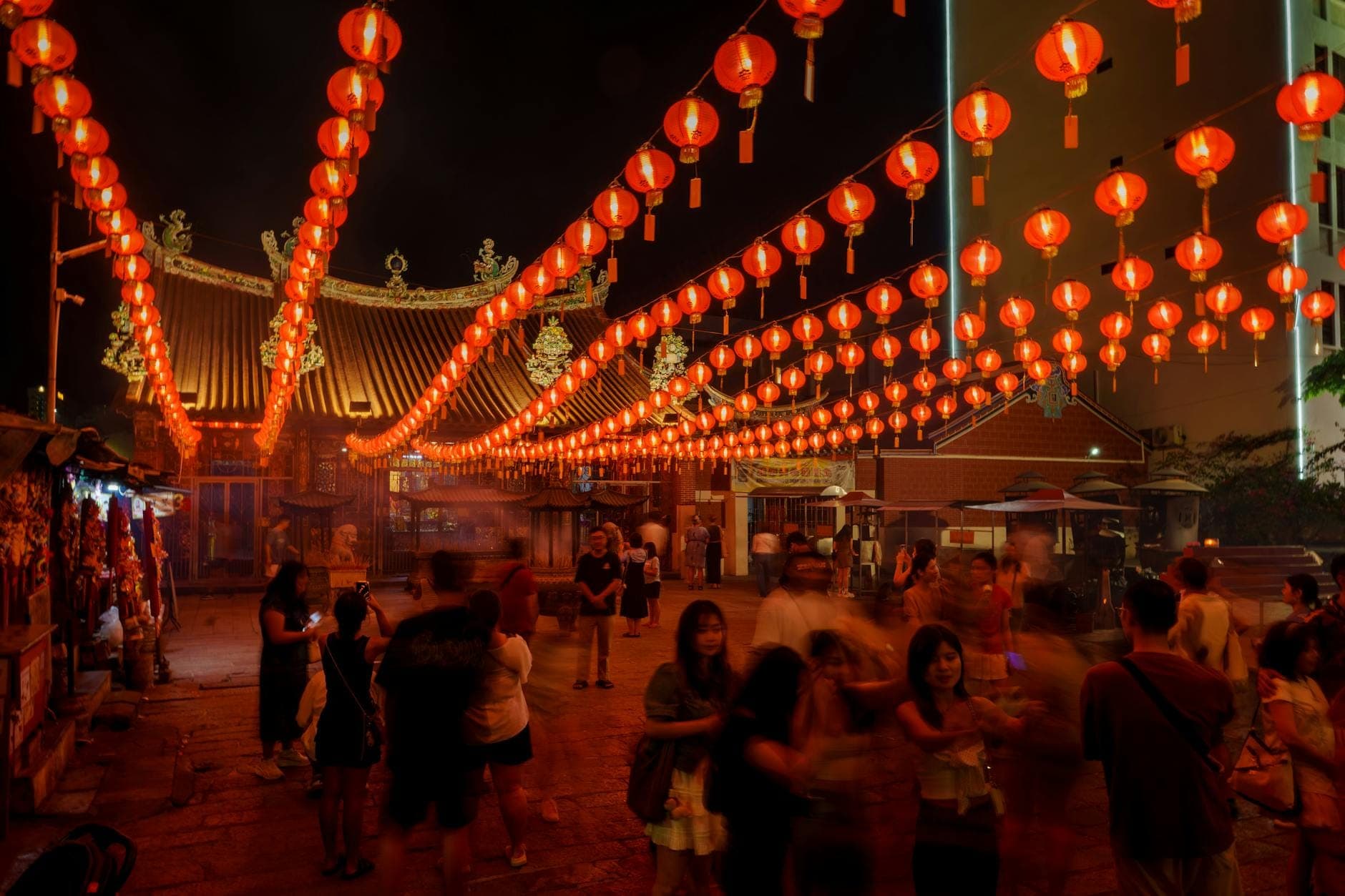 Le calde luci rosse delle lanterne proiettano un bagliore magico su un cortile, creando un'atmosfera notturna vivace e festosa a Kuala Lumpur durante i festeggiamenti del Capodanno Cinese