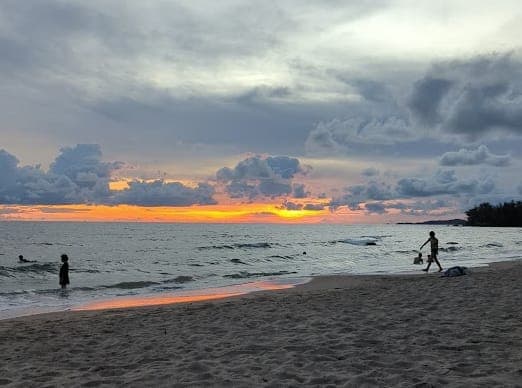 Bãi biển Phú Quốc lúc hoàng hôn với bầu trời nhiều mây và sóng nhẹ trong mùa mưa