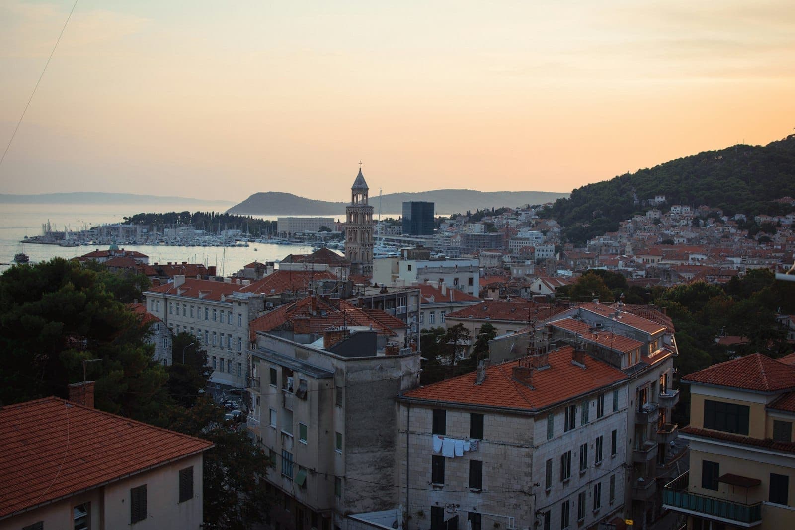 Vista su Spalato durante l'ora d'oro, con campanile, tetti in terracotta, il mare Adriatico e colline lontane sotto un morbido cielo autunnale.