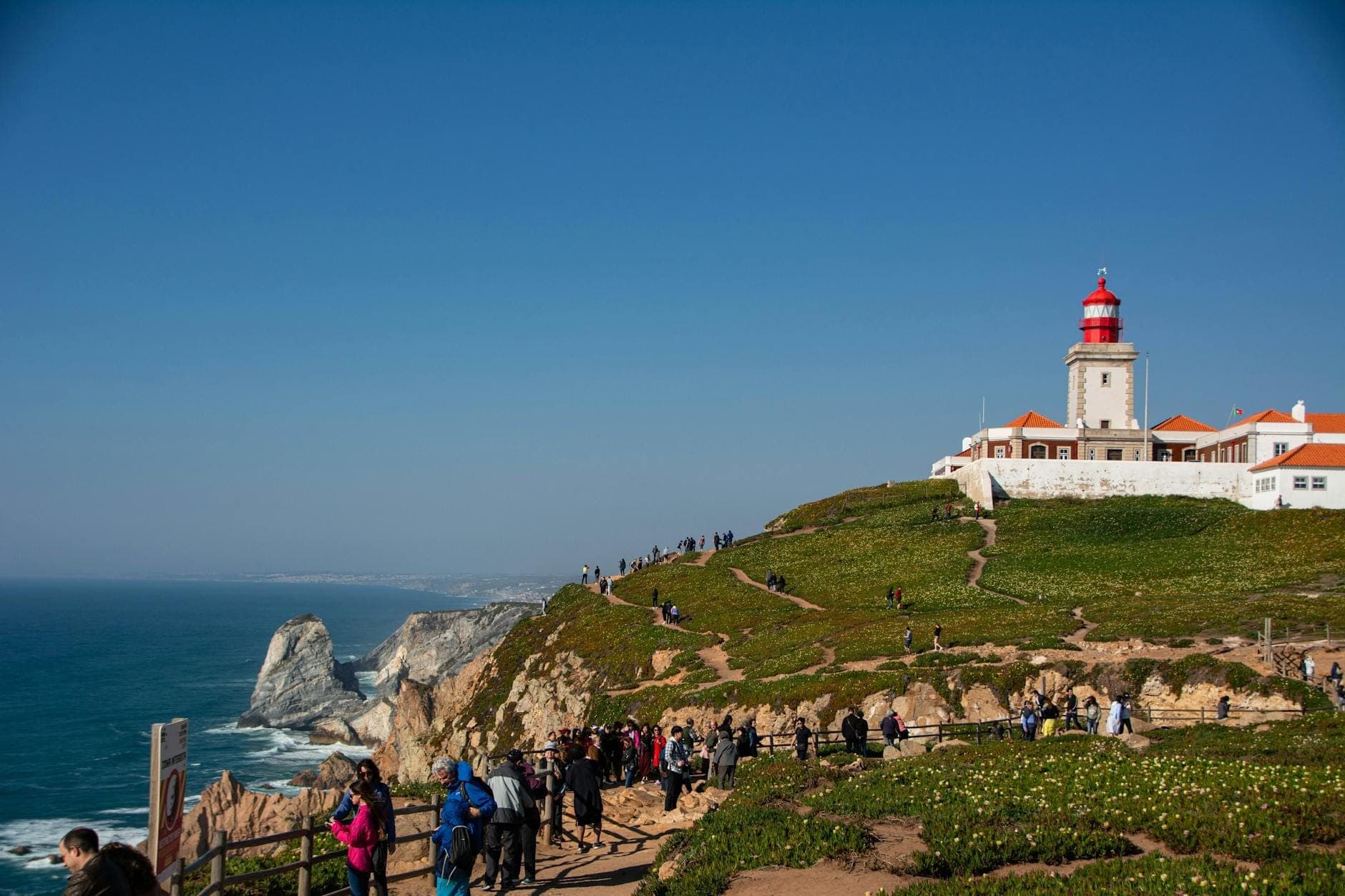 Multidões de pessoas a desfrutar das dramáticas vistas costeiras no farol do Cabo da Roca, nos penhascos com vista para o Oceano Atlântico perto de Lisboa.