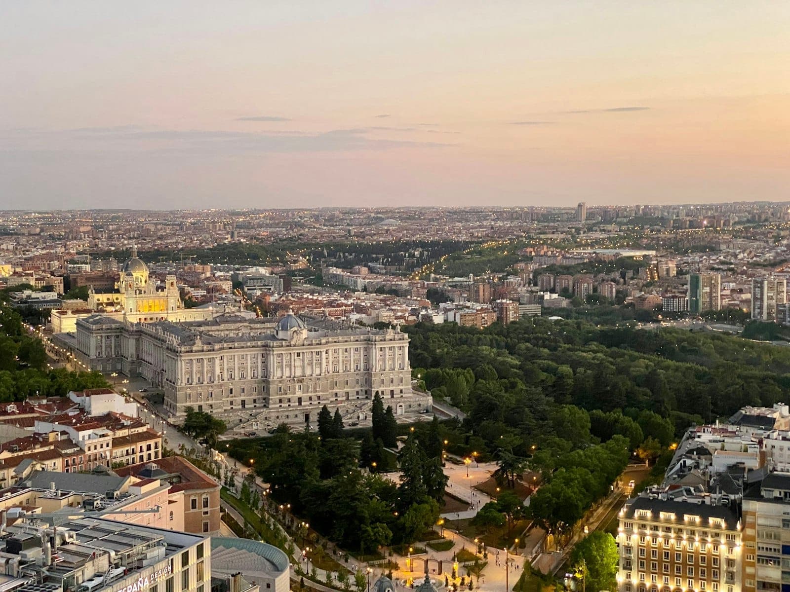 Panoramablick über Madrid mit dem Palacio Real und weitläufigen Grünanlagen bei Sonnenuntergang, ein klassischer Aussichtspunkt über die Stadt.