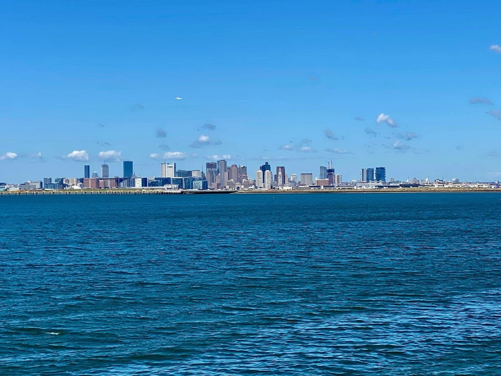Vue lointaine de la ligne d'horizon de Boston sur l'eau bleue, vue depuis les îles du port sous un ciel dégagé.