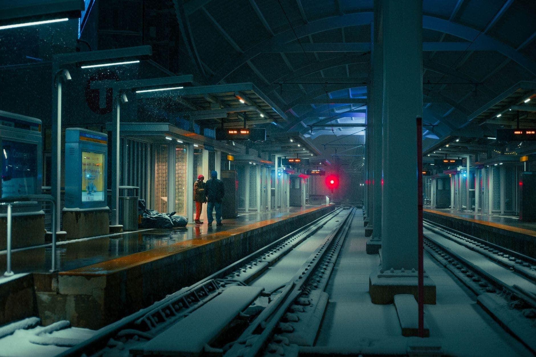 Quai de la station de transit de Boston la nuit avec de la neige au sol et des personnes attendant le train.