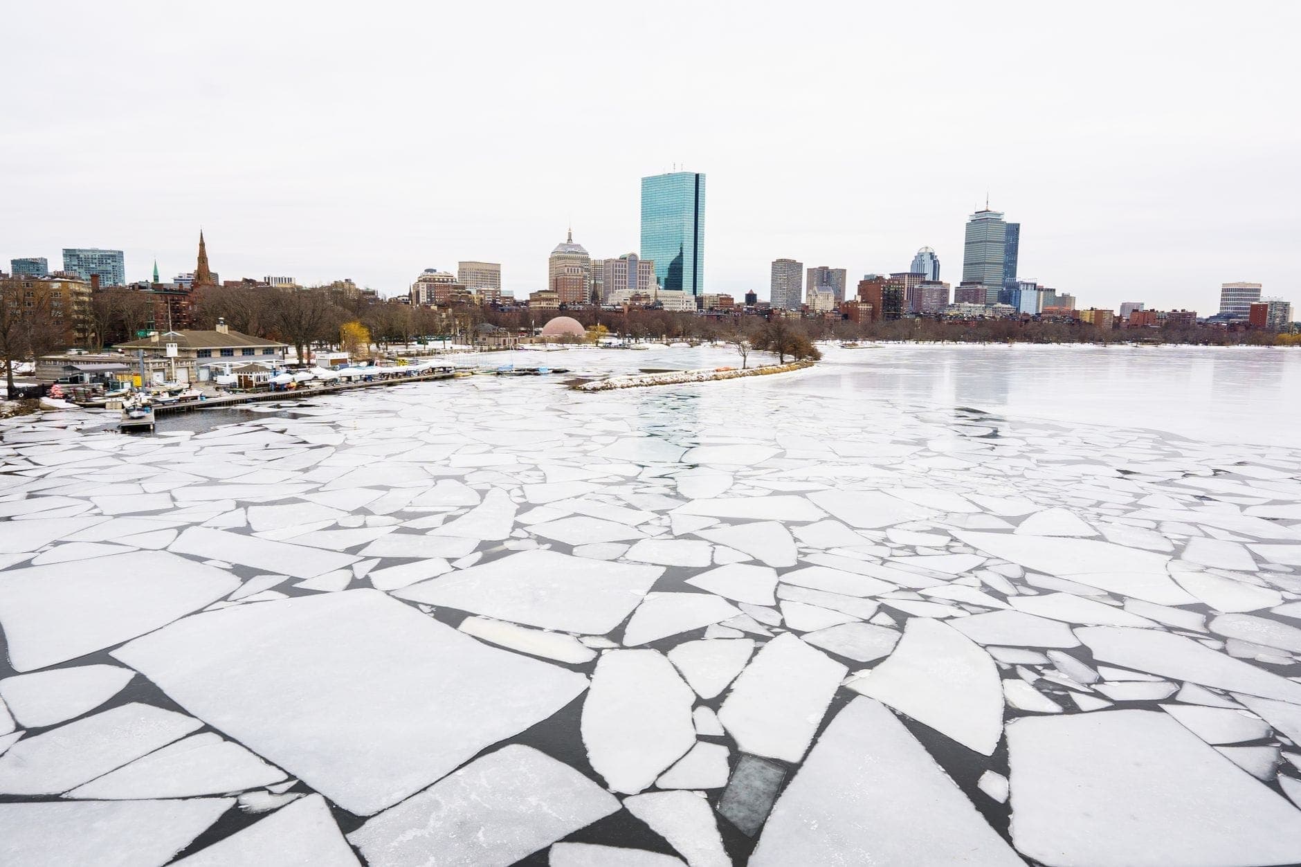 De grands morceaux de glace brisée recouvrant la Charles River gelée avec la skyline de Boston en arrière-plan lors d'une journée d'hiver grise.