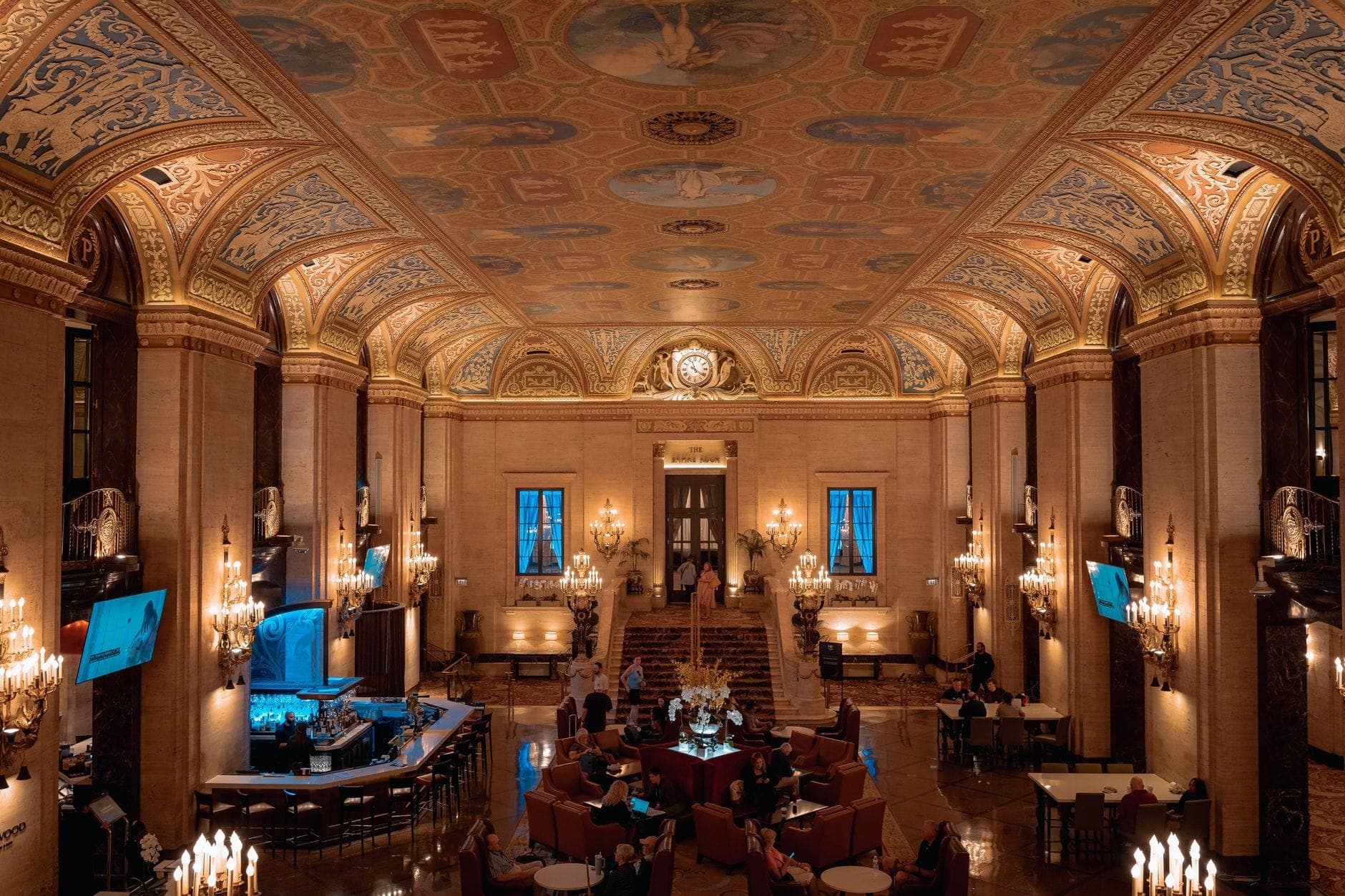 Grand hall d'hôtel de luxe avec plafonds ornés, lustres et espaces lounge élégants, incarnant le raffinement et l'hospitalité haut de gamme de Boston.