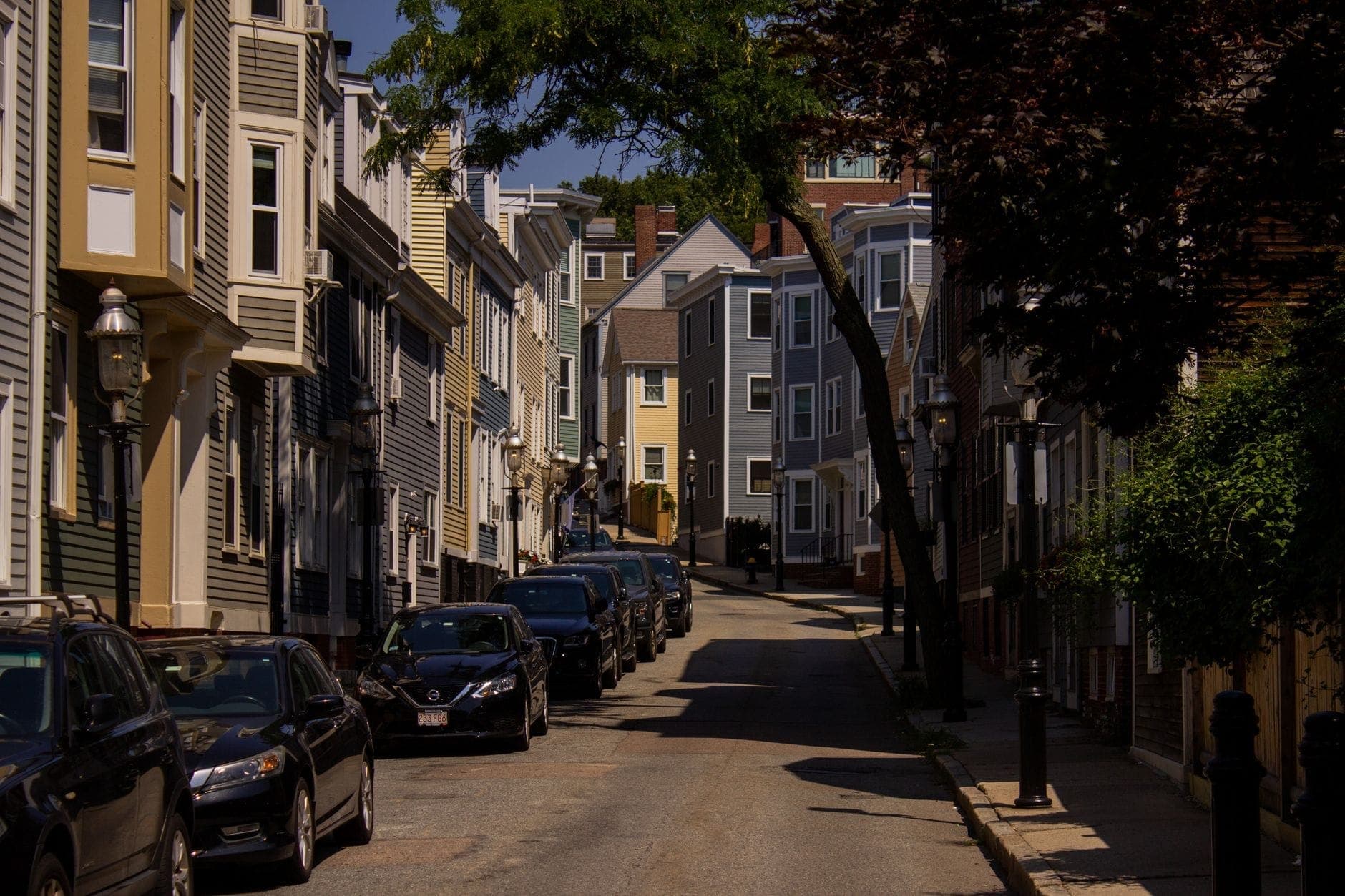 Rue résidentielle de Boston bordée de maisons en rangée et de voitures garées, illustrant les quartiers juste en dehors du centre-ville.