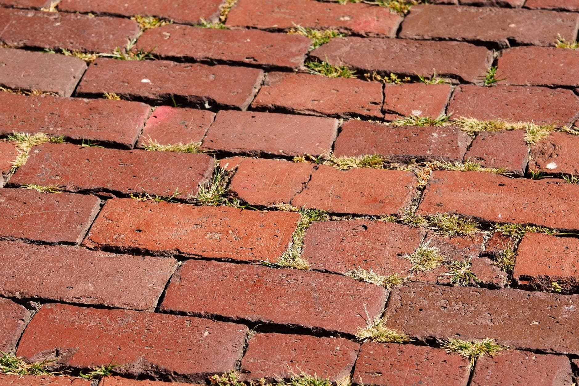 Gros plan d'un trottoir historique en briques rouges, évocateur du Freedom Trail de Boston et des itinéraires historiques à pied.