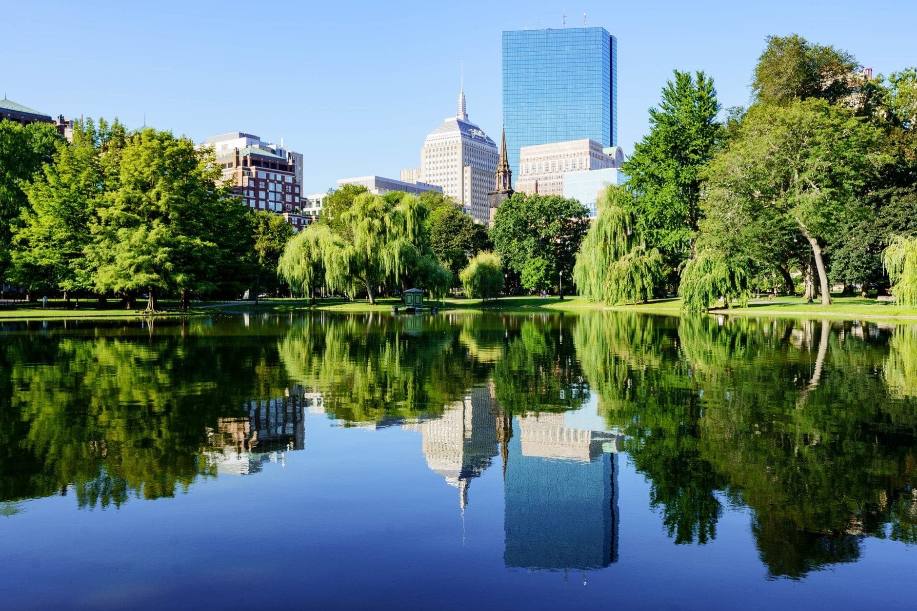 Boston Public Garden avec la skyline et les saules reflétés dans l'étang par une journée ensoleillée