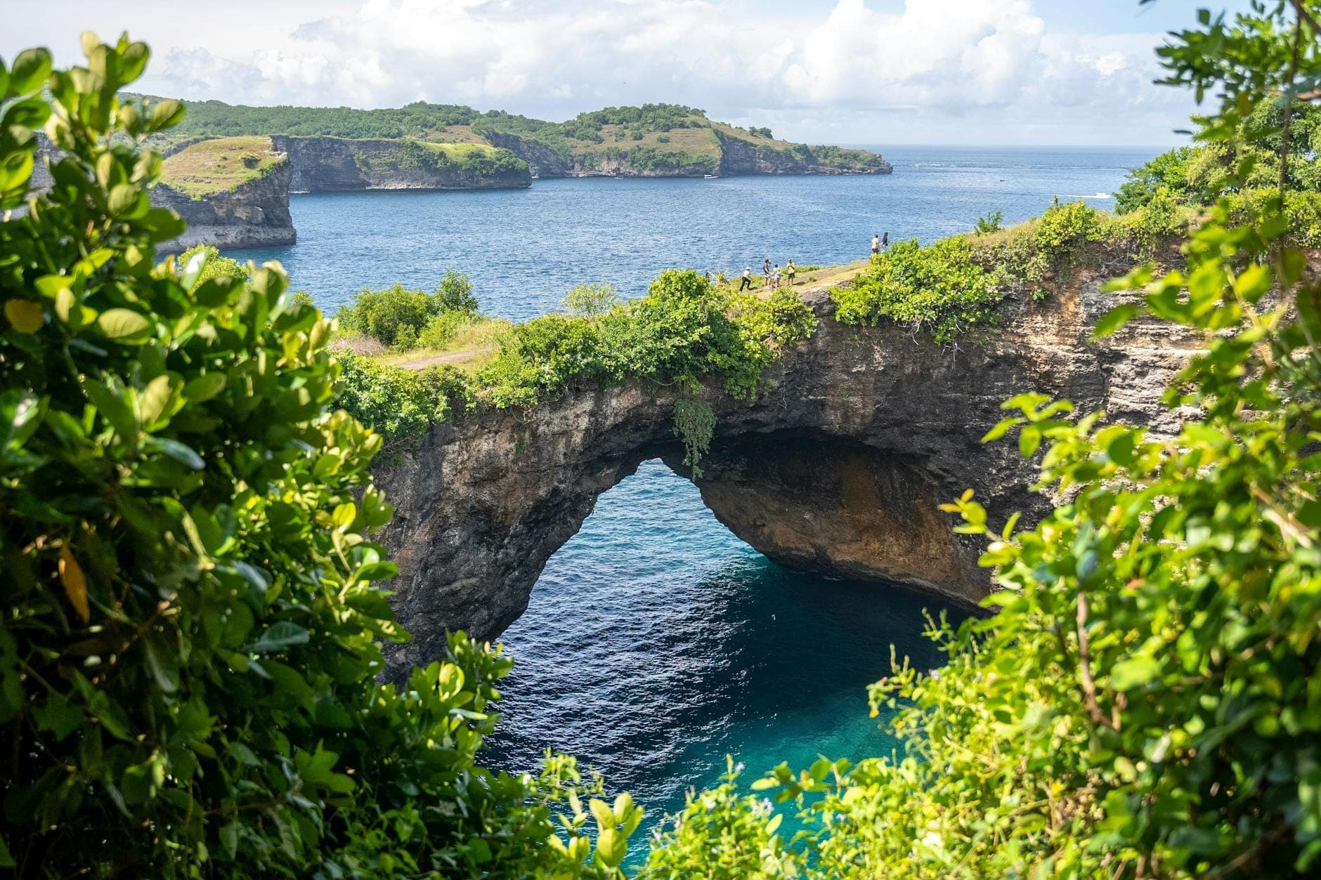 Natural stone archway and circular turquoise cove at Broken Beach (Pasih Uug) on Nusa Penida, Bali viewed from the clifftop