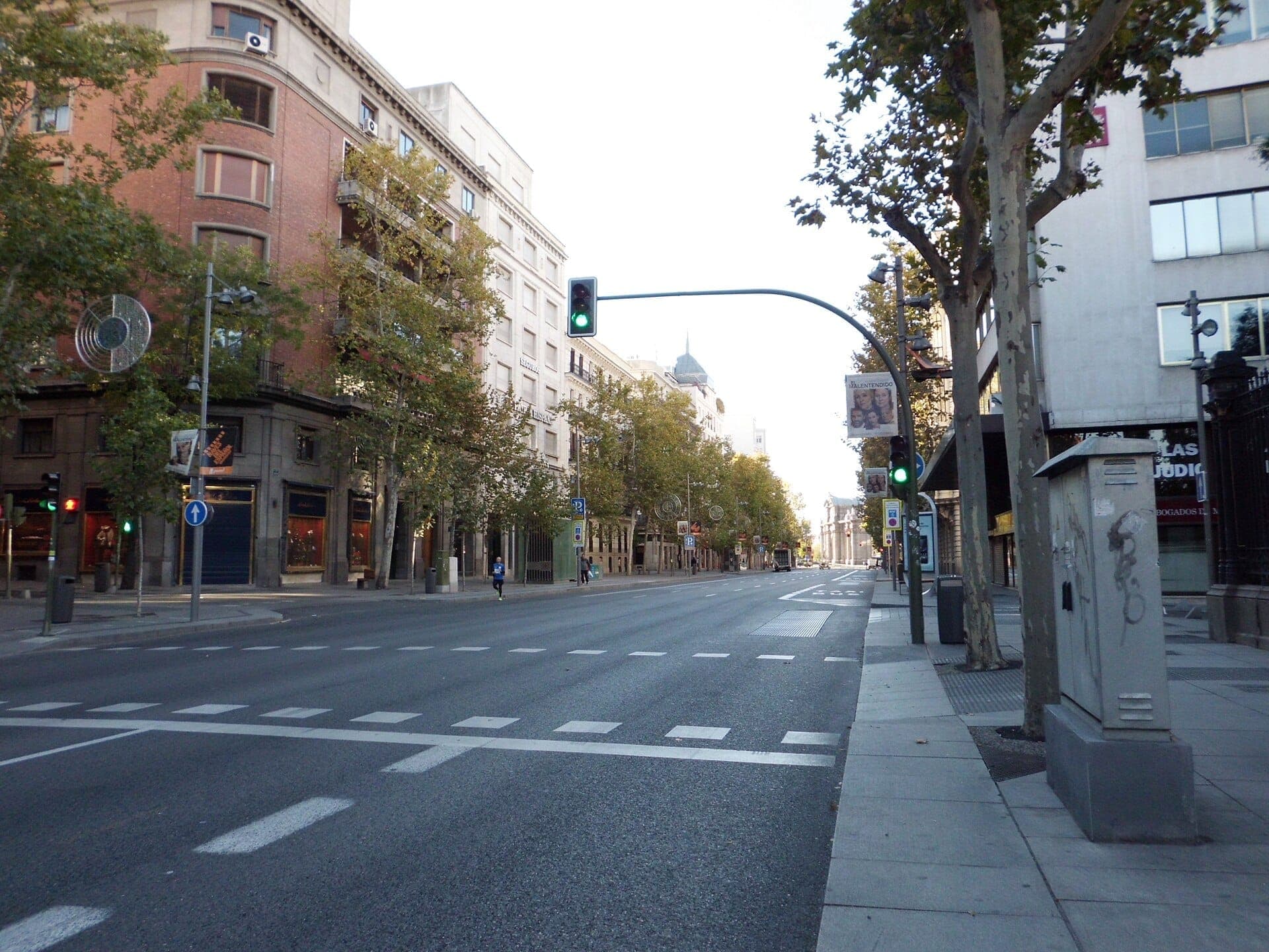 Calle de Serrano ในกรุงมาดริดในยามเช้าที่เงียบสงบ เรียงรายด้วยอาคารสง่างาม ร้านบูติก และต้นไม้ใบหนาแน่นใต้ท้องฟ้าแจ่มใส