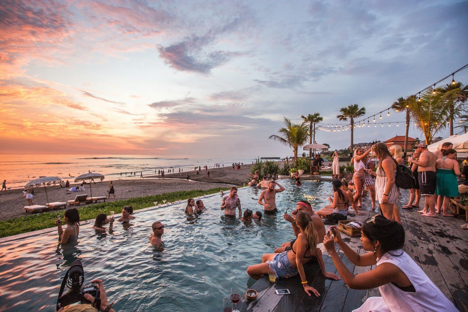 Scenic Canggu beach coastline with golden sand, crashing waves, and vibrant beach clubs during daytime