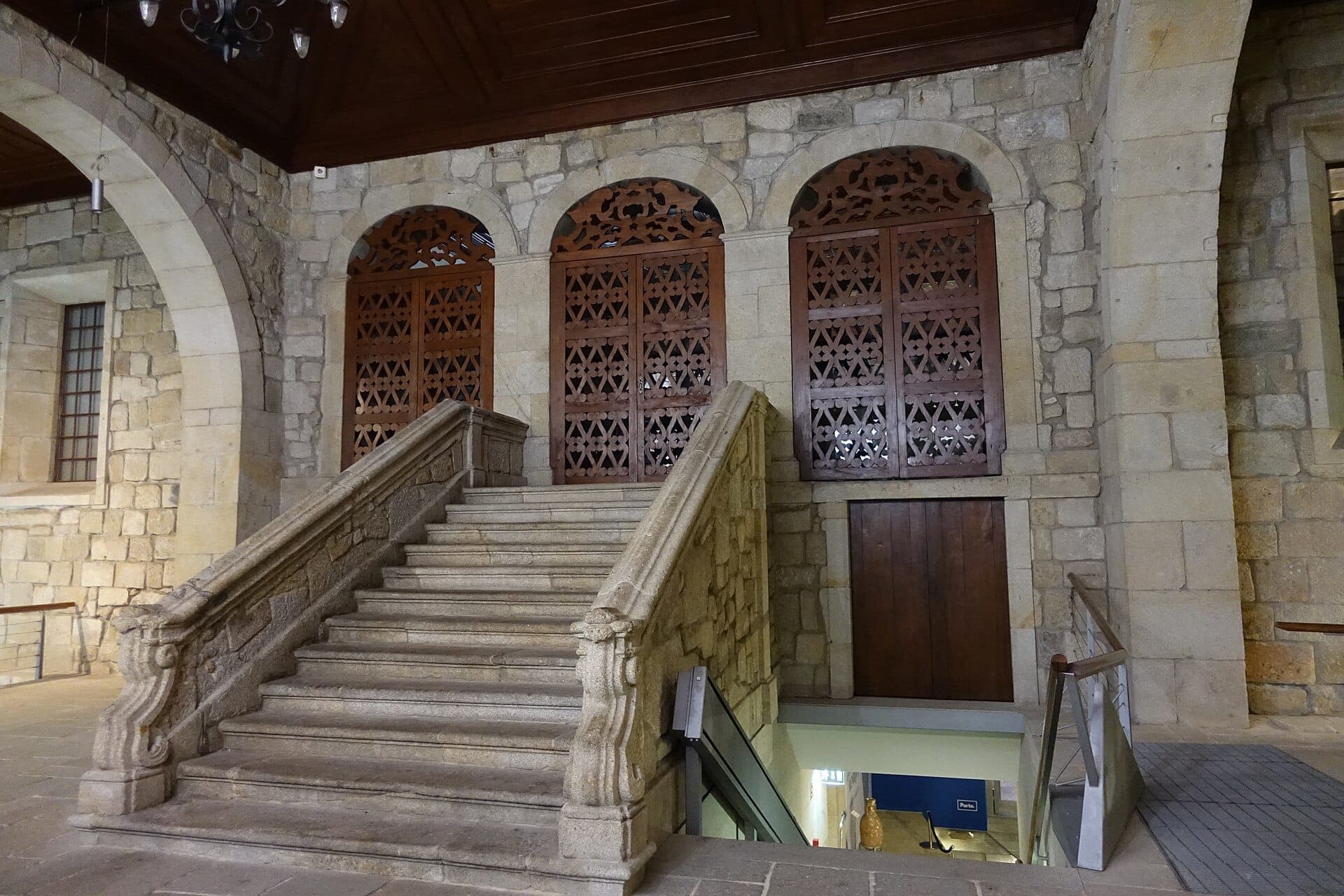 Escalier en pierre et fenêtres à treillis de bois en arc à l'intérieur de la Casa do Infante, illustrant l'architecture historique du plus ancien bâtiment civique de Porto.