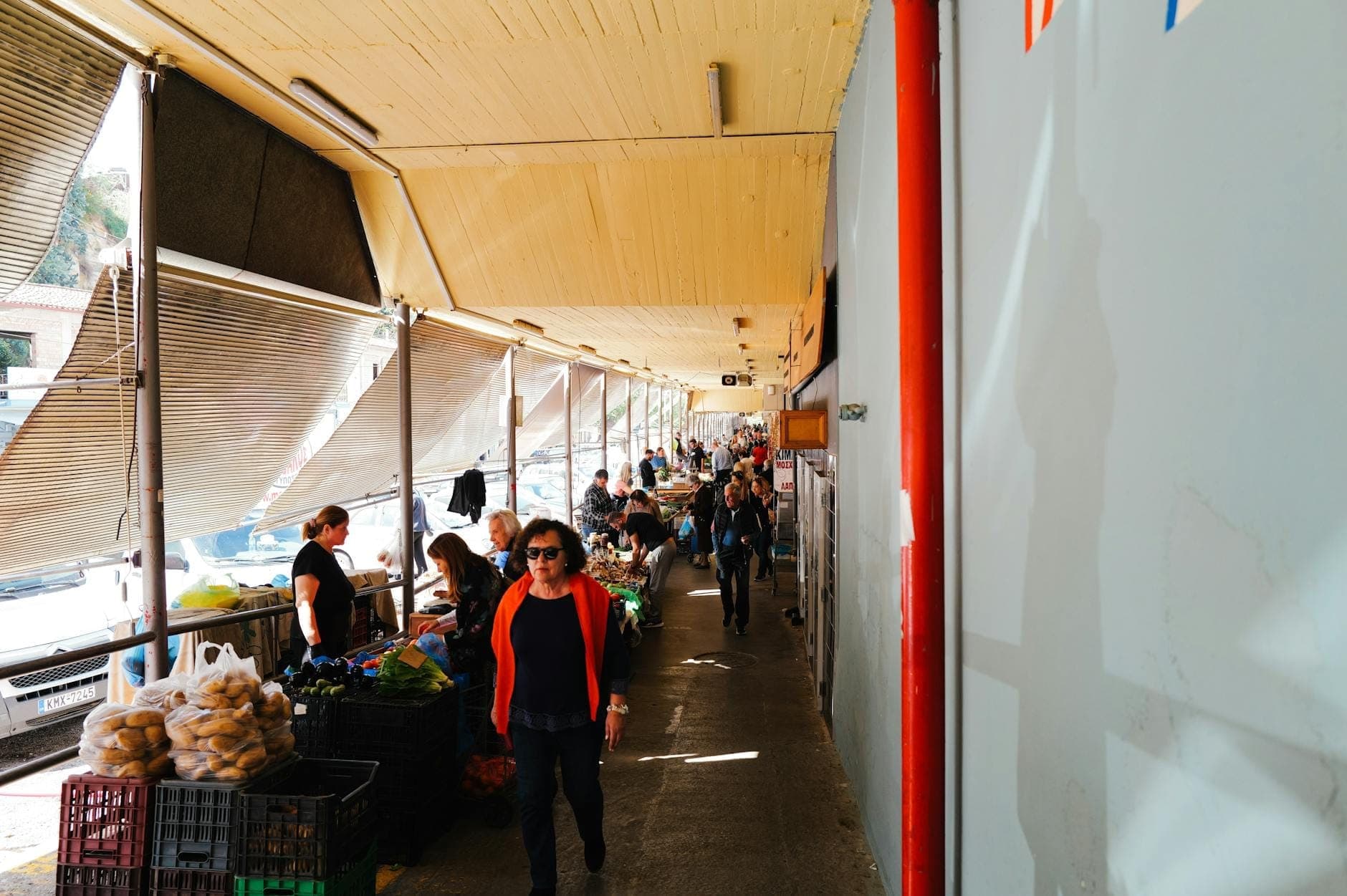 Freiluft-Markt auf Kreta mit Menschen, die unter einem überdachten Gang frisches Gemüse einkaufen.