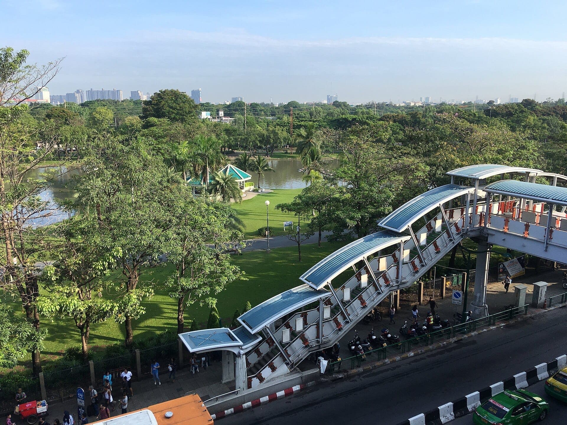 Grande pelouse verdoyante bordée d'arbres dans le parc Chatuchak à Bangkok, espaces ombragés et ambiance paisible de parc urbain