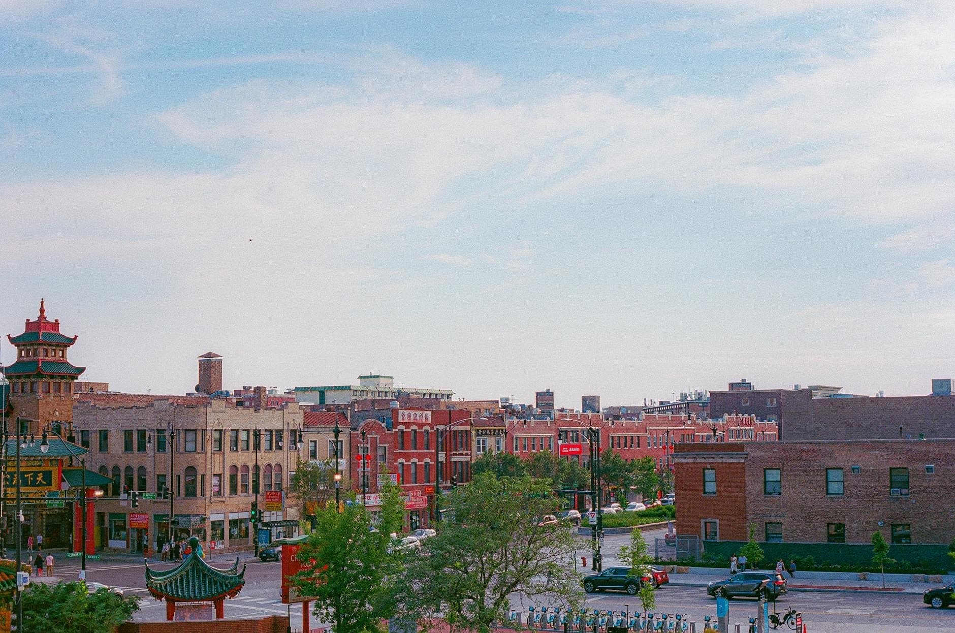 Daytime view overlooking Chicago's Chinatown, with traditional Chinese architecture, red buildings, pagoda roofs, and Wentworth Avenue visible under a blue sky.