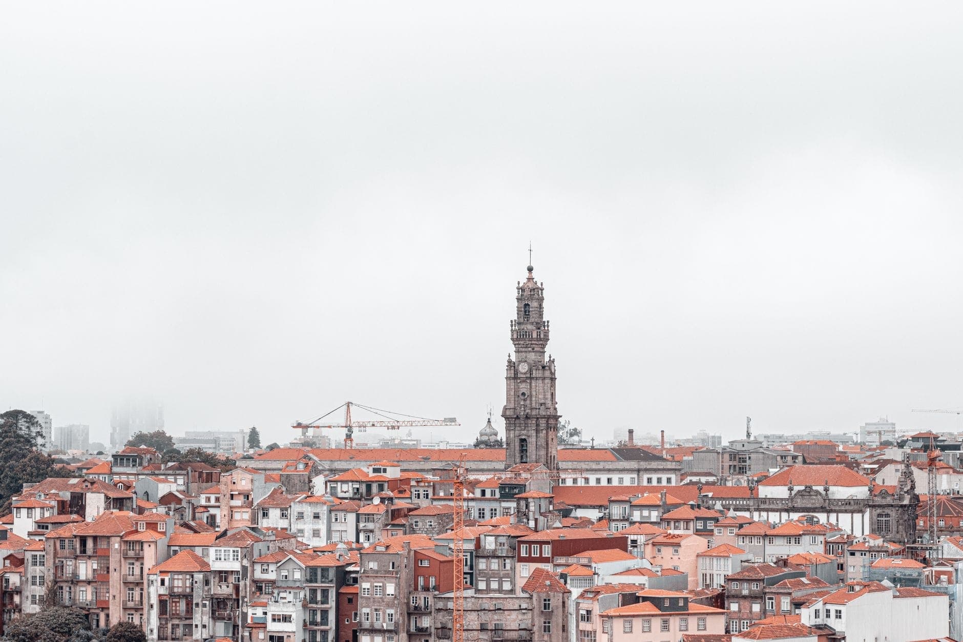 Der Clérigos-Turm erhebt sich über die historische Altstadt Portos mit ihren rotgedeckten Häusern unter einem bewölkten Himmel – das unbestrittene Highlight der Skyline.