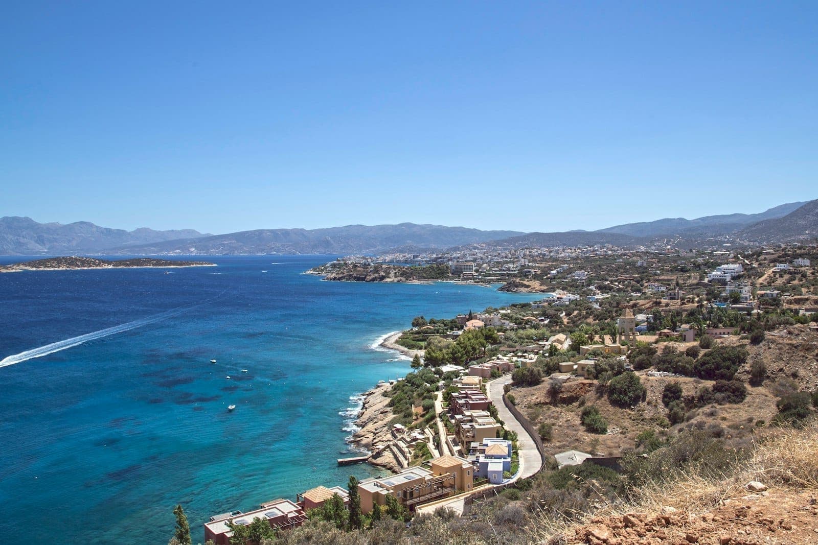 Weiter Küstenblick auf Kreta mit klarem blauem Meer, sonnigem Himmel und Küstendörfern entlang der Küstenlinie bei Oktoberwetter.