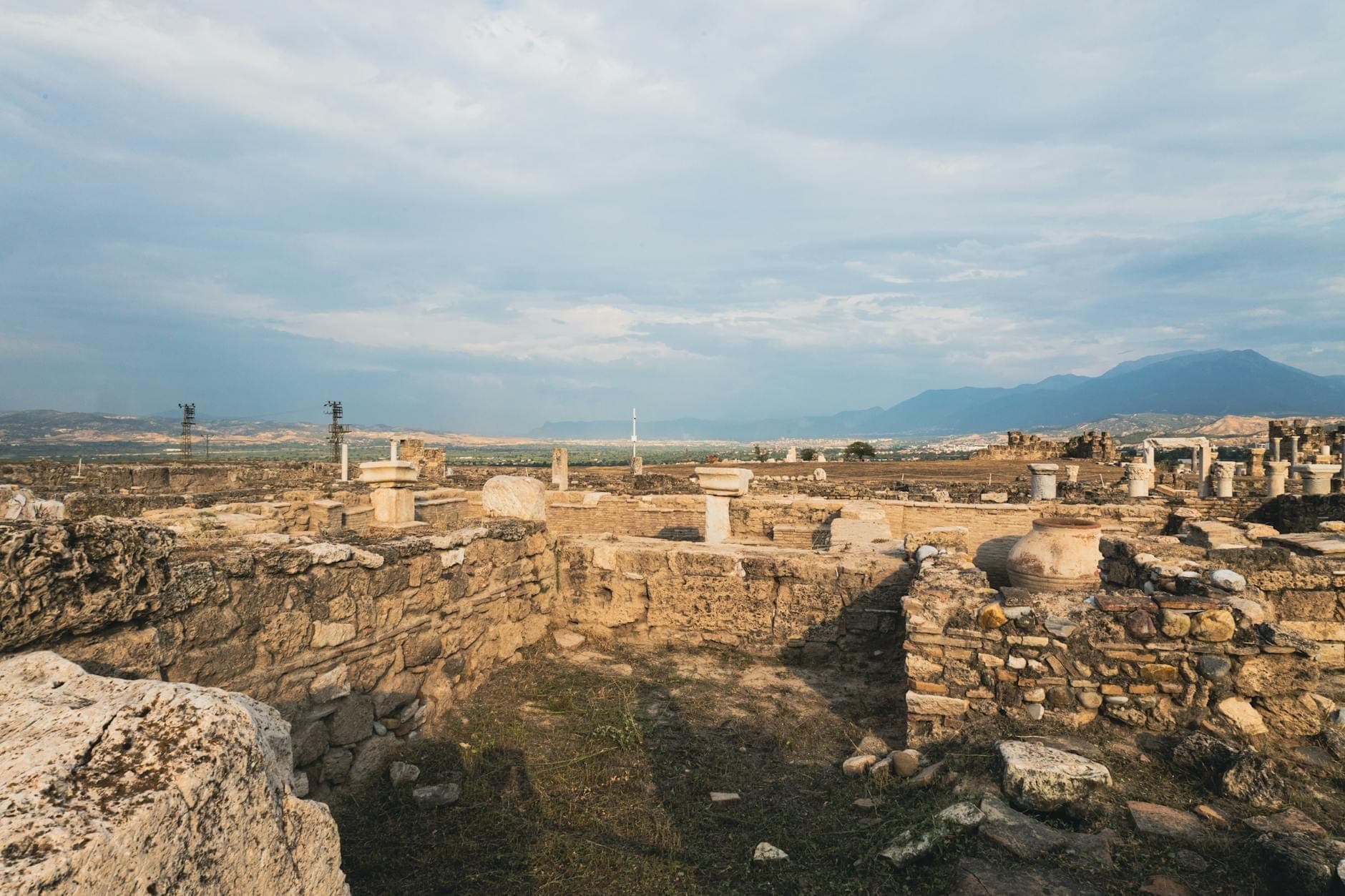 Vista ampia di antiche rovine in pietra e colonne nella pianura di Messara con paesaggio altipiano e montagne lontane a Creta.